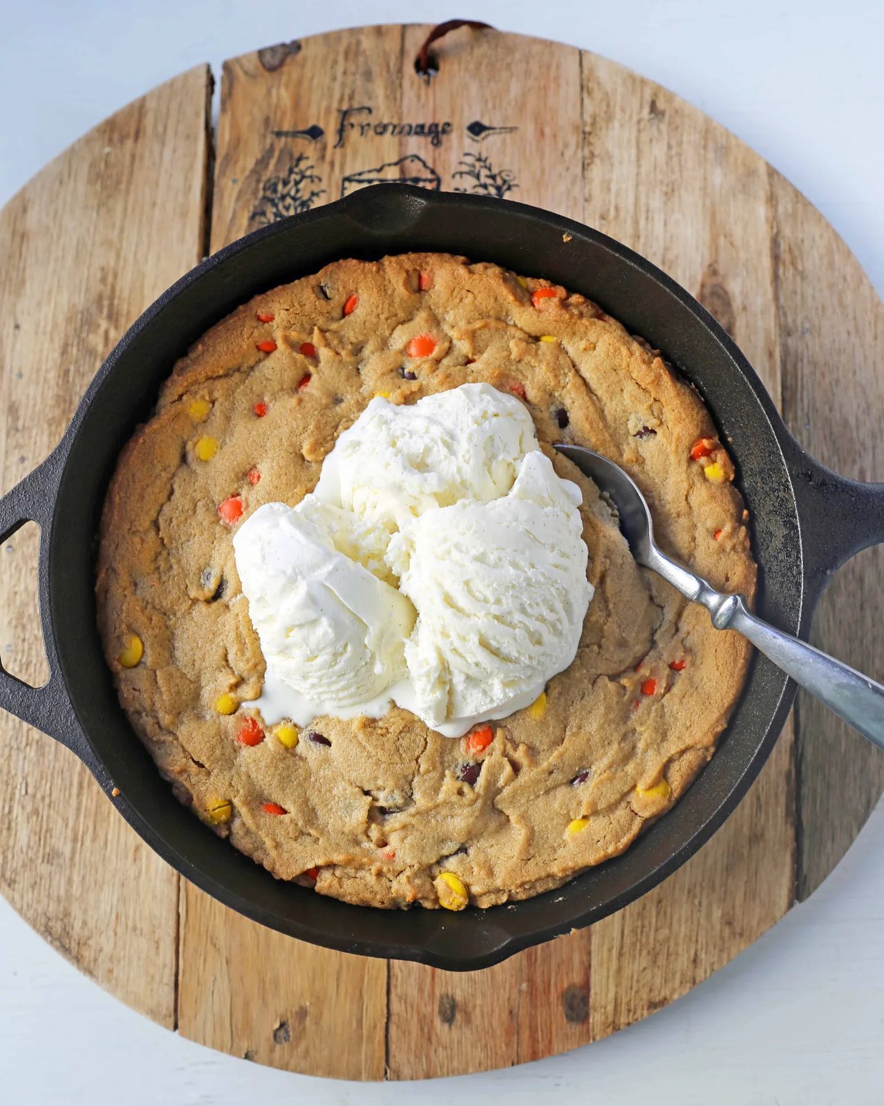 Peanut Butter Skillet Cookie. Homemade peanut butter cookie dough with Reeses Pieces baked until ooey gooey and topped with vanilla ice cream and hot fudge. www.modernhoney.com #peanutbutter #peanutbuttercookies #peanutbutterpizookie #pizookie