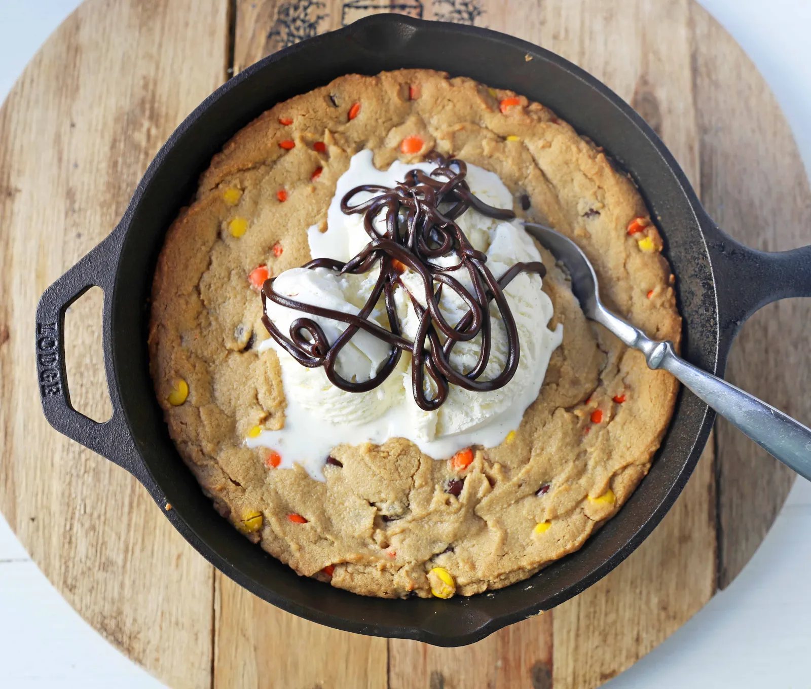 Peanut Butter Skillet Cookie. Homemade peanut butter cookie dough with Reeses Pieces baked until ooey gooey and topped with vanilla ice cream and hot fudge. www.modernhoney.com #peanutbutter #peanutbuttercookies #peanutbutterpizookie #pizookie