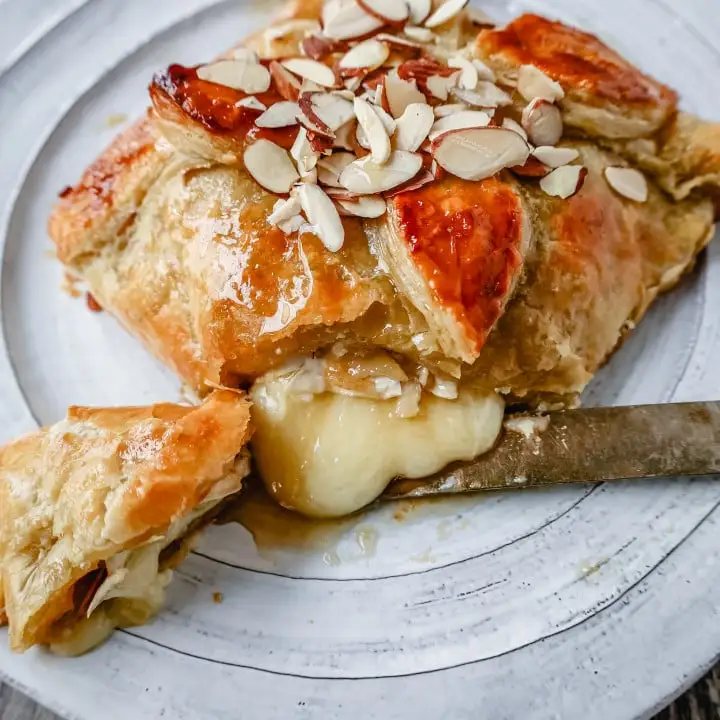 Honey Almond Puff Pastry Wrapped Brie Brie cheese wrapped in buttery puff pastry with local honey and sliced almonds. This is a sweet and salty festive party appetizer.