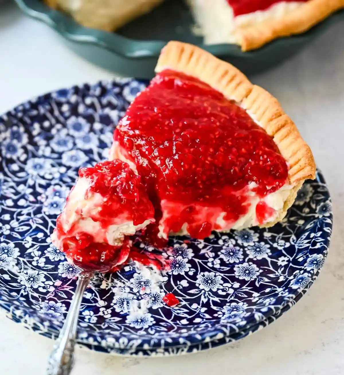 This homemade Raspberry Cream Pie is made with a sweet vanilla cream cheese cheesecake filling topped with a homemade raspberry sauce, all in a buttery, flaky homemade crust. This is a homemade take on the famous Briermere Farms raspberry cream pie and the perfect summer dessert that can be made with fresh or frozen raspberries.