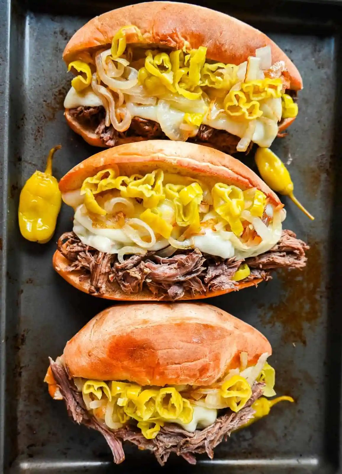 The Best Slow Cooker Italian Beef Sandwiches. These Crockpot Italian Beef Sandwiches are made with flavorful slow cooked beef, shredded to perfection, and placed in a buttered bun, and topped with melted provolone cheese, caramelized onions, and pepperoncini peppers.