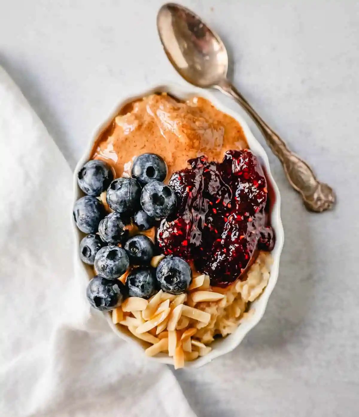Oatmeal with Almond Butter, Jam, and Almonds. How to make creamy oatmeal with your favorite toppings combinations. I am sharing a list of all of the popular oatmeal toppings ideas to serve on a cold winter day and how to make the best bowl of oatmeal!