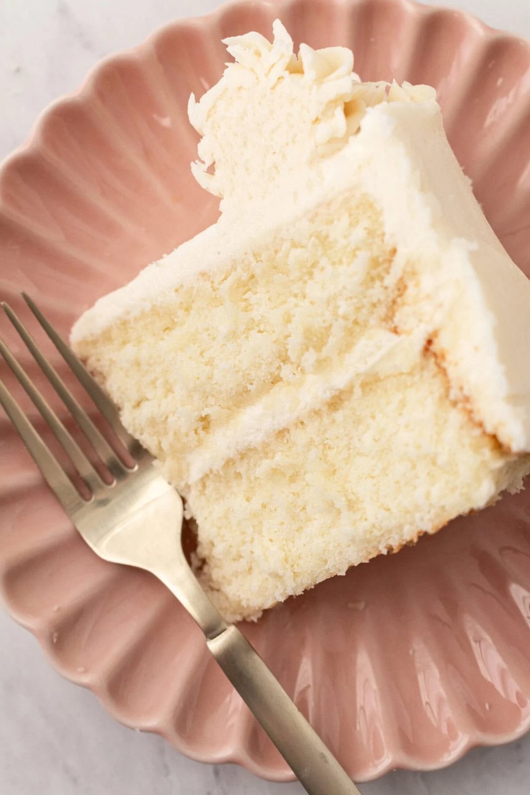 A slice of vanilla cake. The best homemade vanilla cake recipe with vanilla bean buttercream frosting. If you’re looking for the best homemade vanilla cake recipe, this is it! This moist and fluffy vanilla cake is easy to make from scratch using simple ingredients. Perfect for birthdays or celebrations. This white cake recipe features a light, airy crumb and the most tender texture. This is a bakery-worthy dessert!
