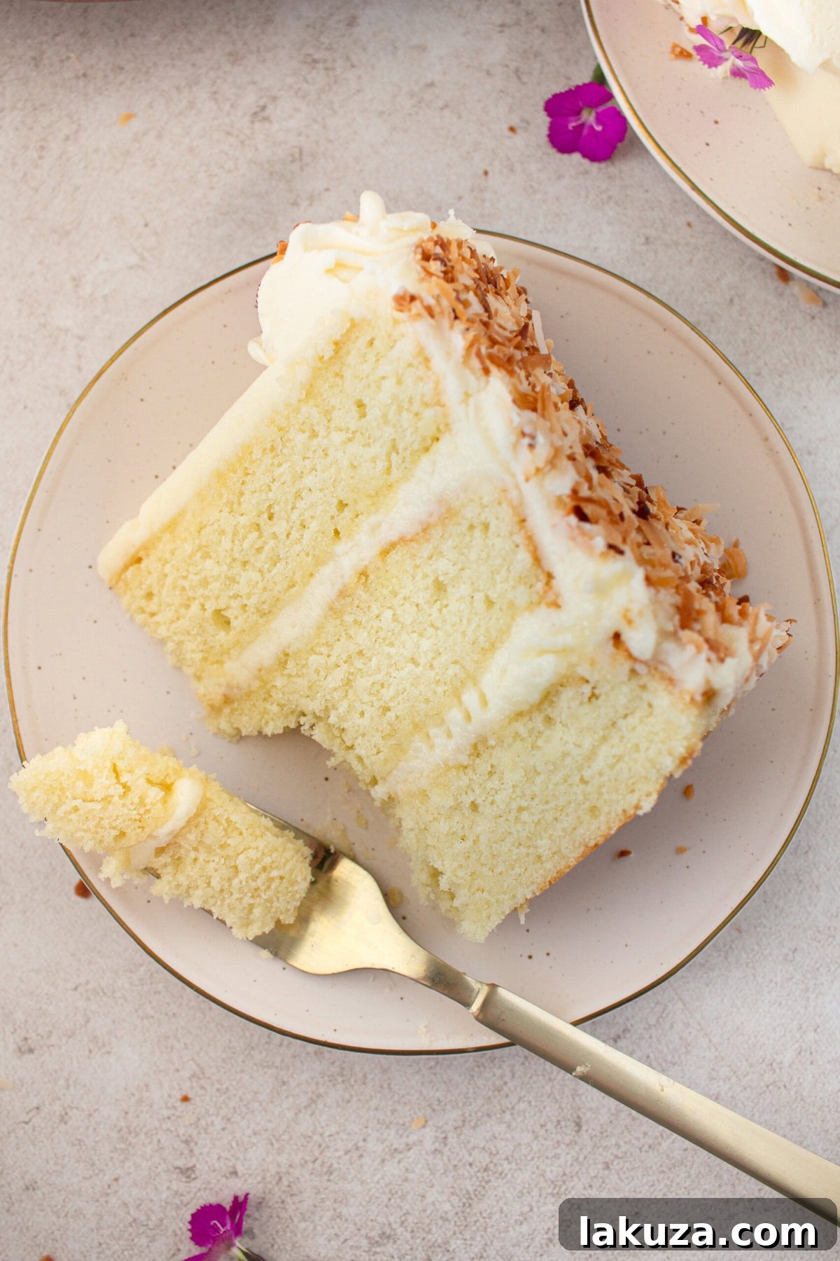 A mouthwatering slice of moist coconut cake with coconut cream cheese frosting, garnished with fresh coconut. This best coconut cake recipe ensures an extra tender texture.