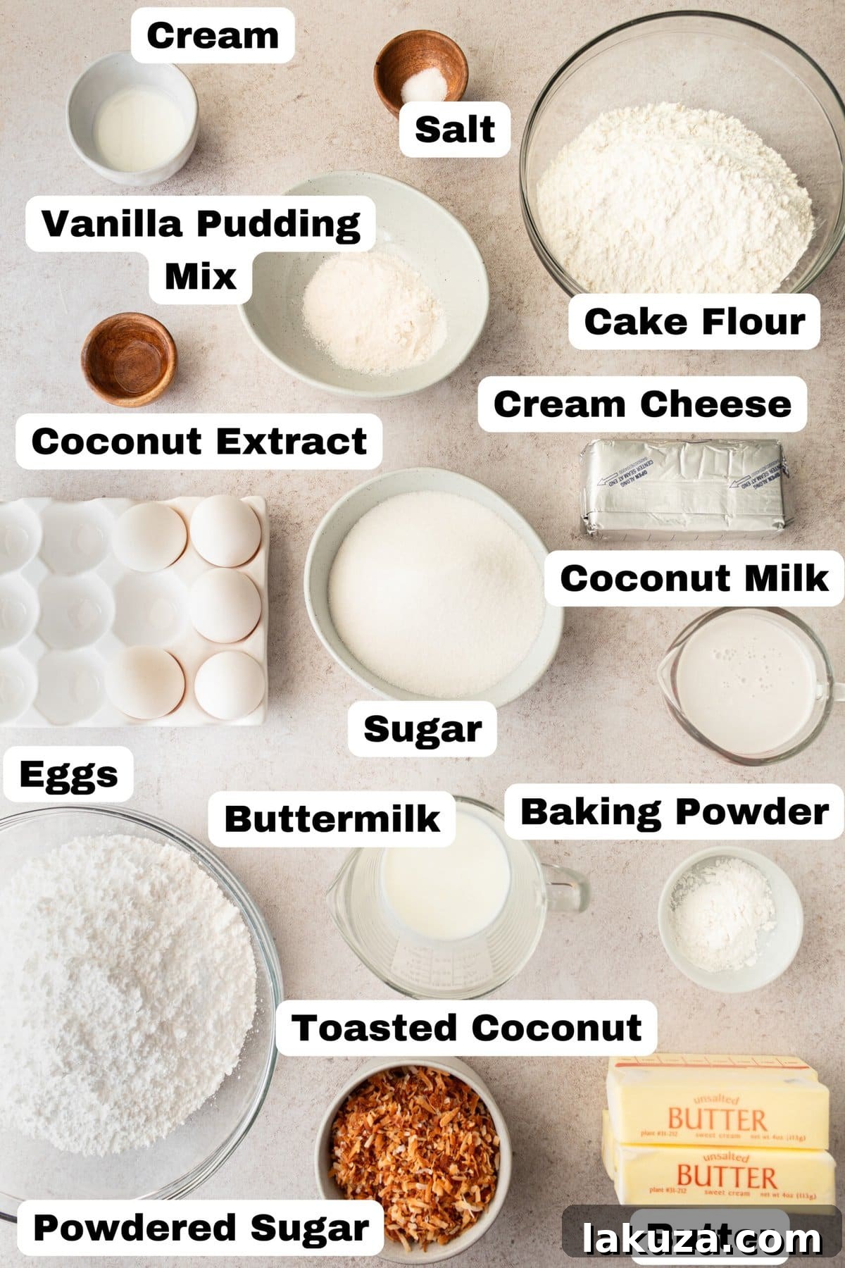 A selection of key ingredients for homemade coconut cake, including cake flour, butter, coconut milk, and eggs, laid out on a kitchen counter.