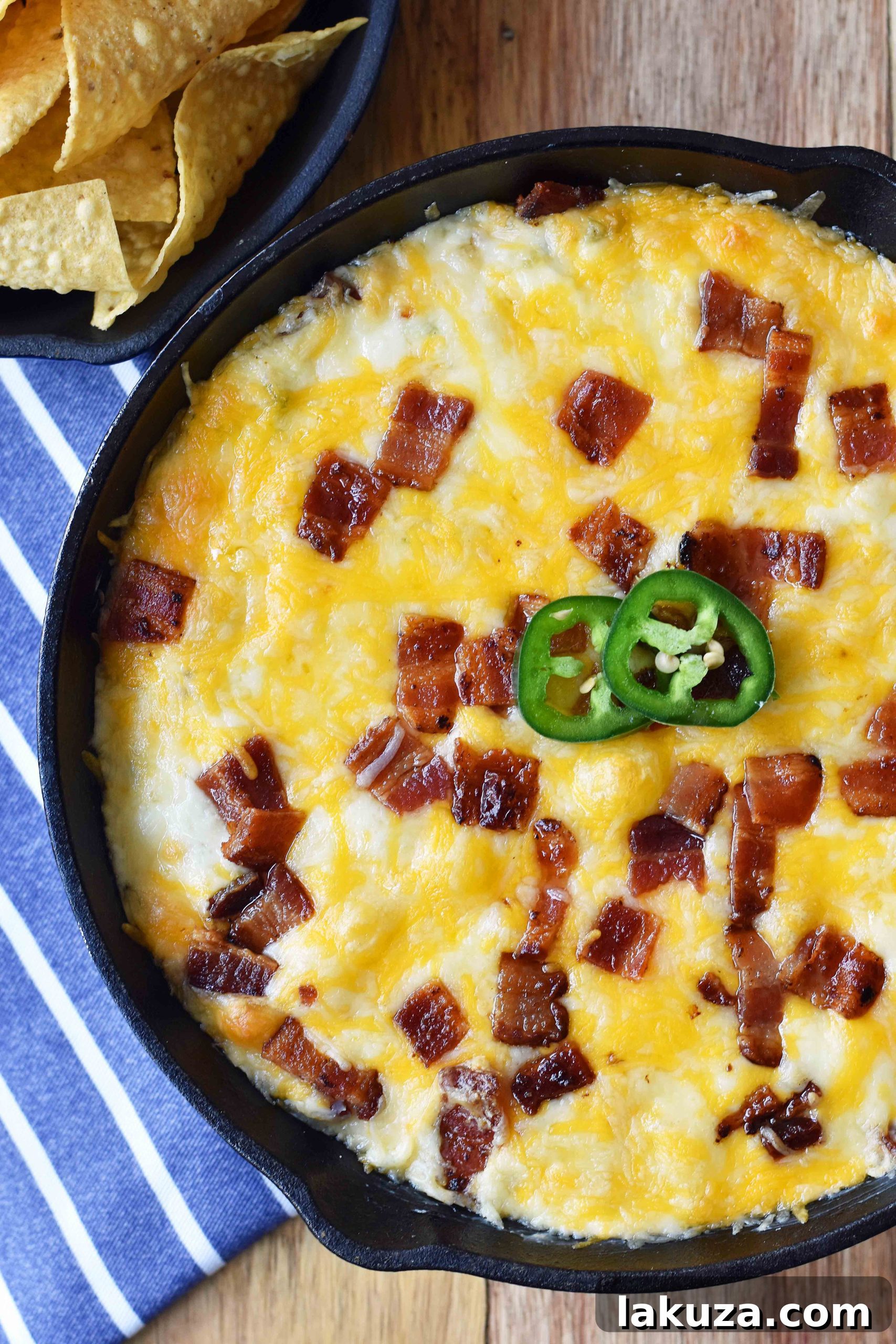 Close-up of Creamy Jalapeno Popper Dip with Bacon in a cast iron skillet, garnished with fresh cilantro, ready to be served. Perfect for parties.