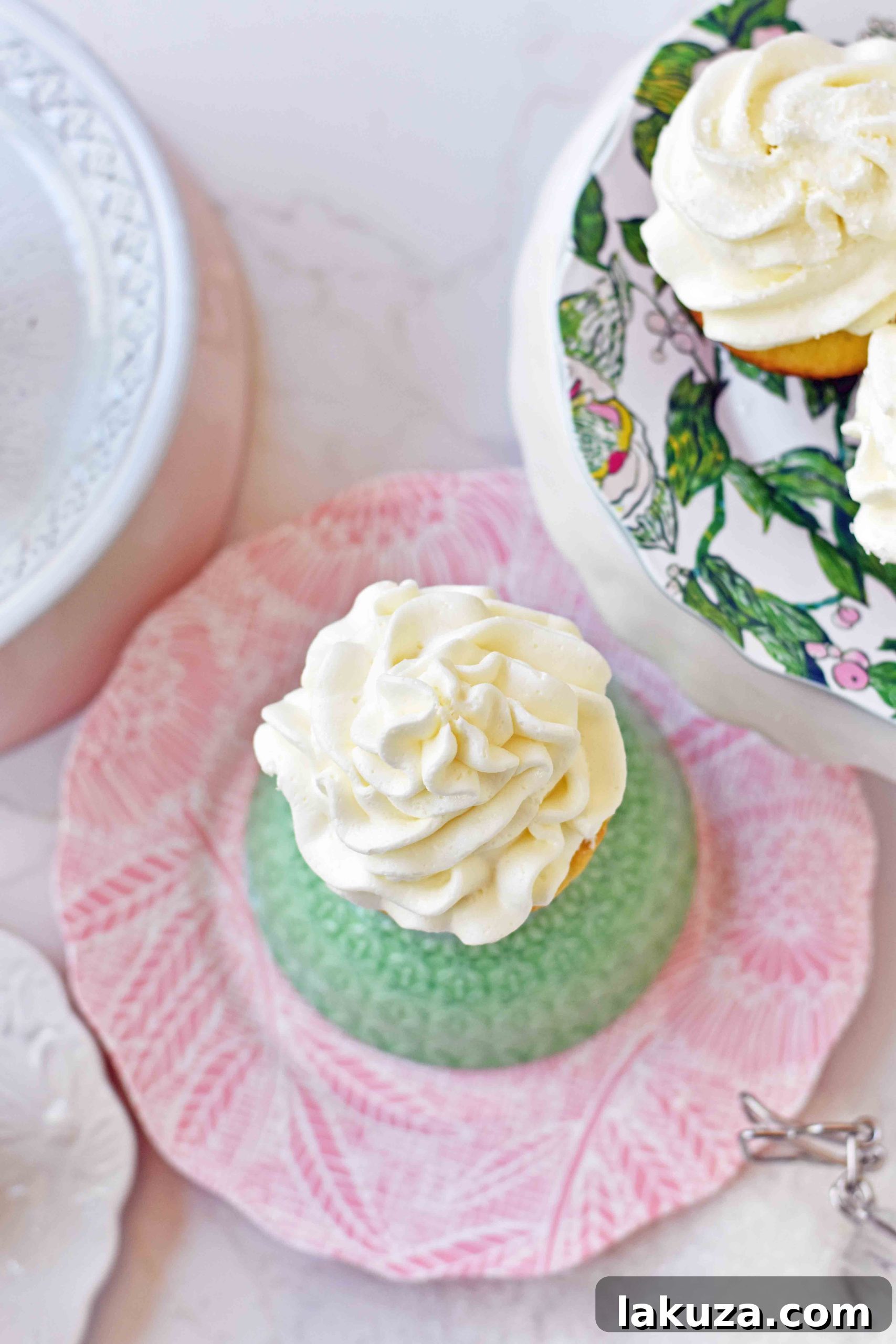 Perfect Vanilla Cupcakes 7 A freshly frosted vanilla cupcake with a decorative swirl of buttercream, resting on a white plate.