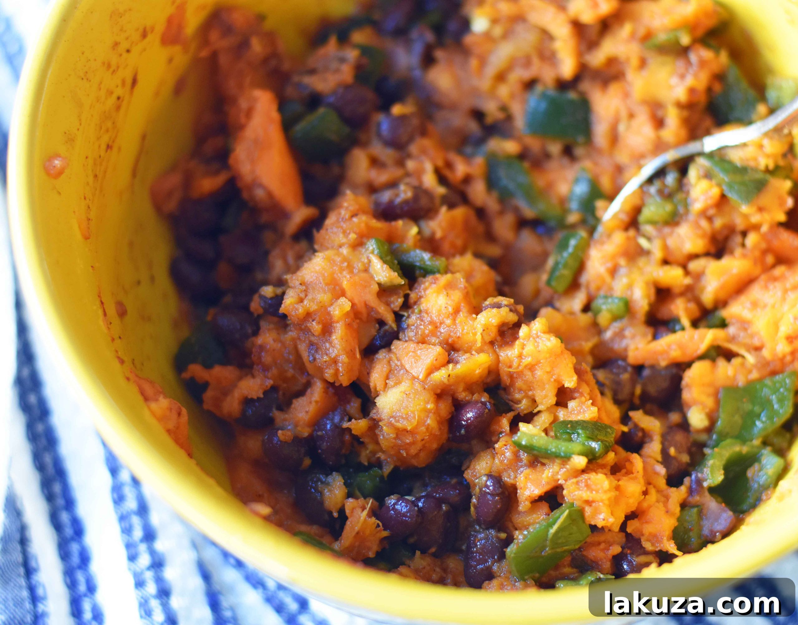 Zesty Sweet Potato and Black Bean Enchiladas 5 A large mixing bowl filled with the prepared sweet potato and black bean filling, showcasing mashed sweet potatoes, diced poblano peppers, and black beans, ready for assembly.