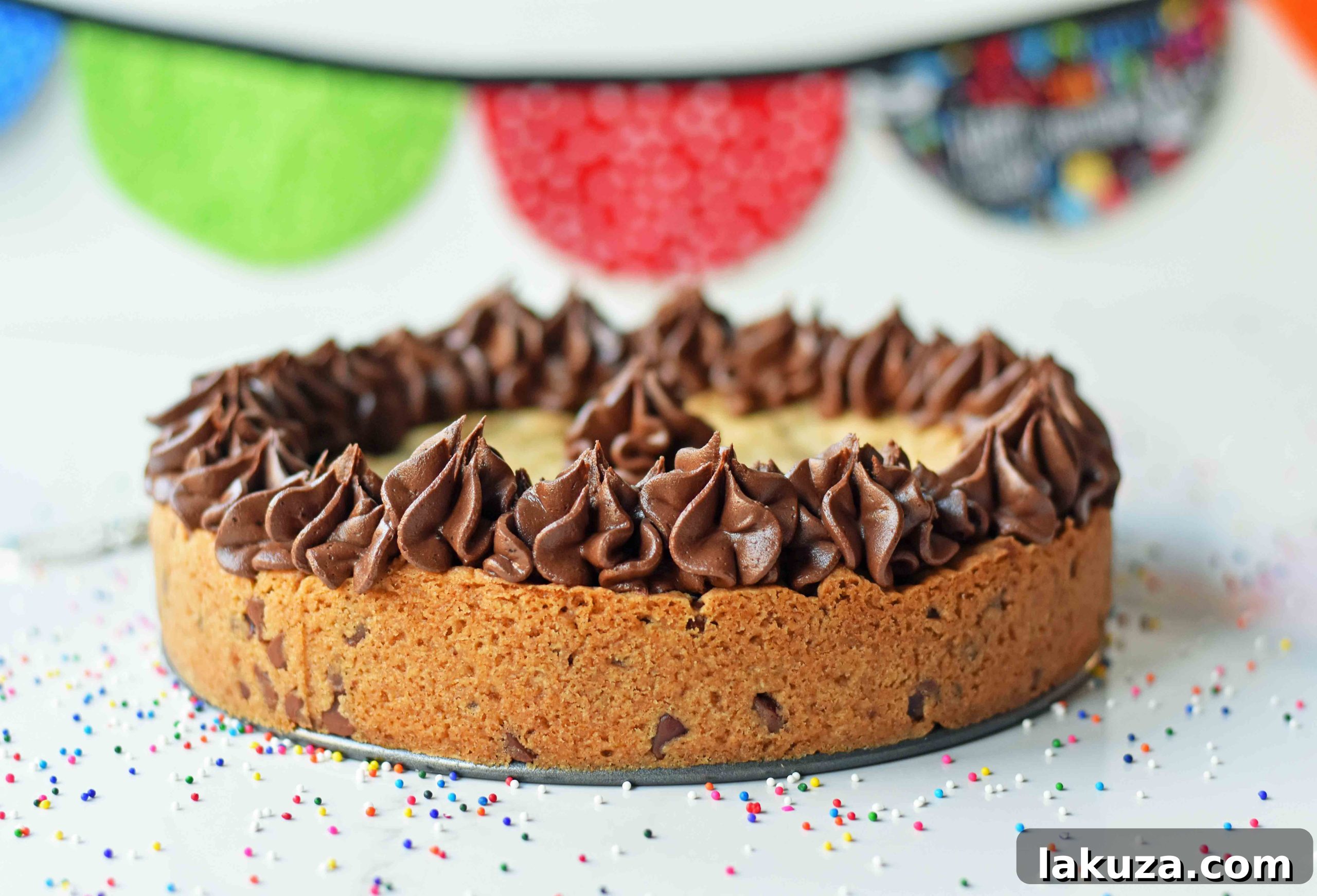 Close-up of a festive chocolate chip cookie cake with colorful frosting decorations