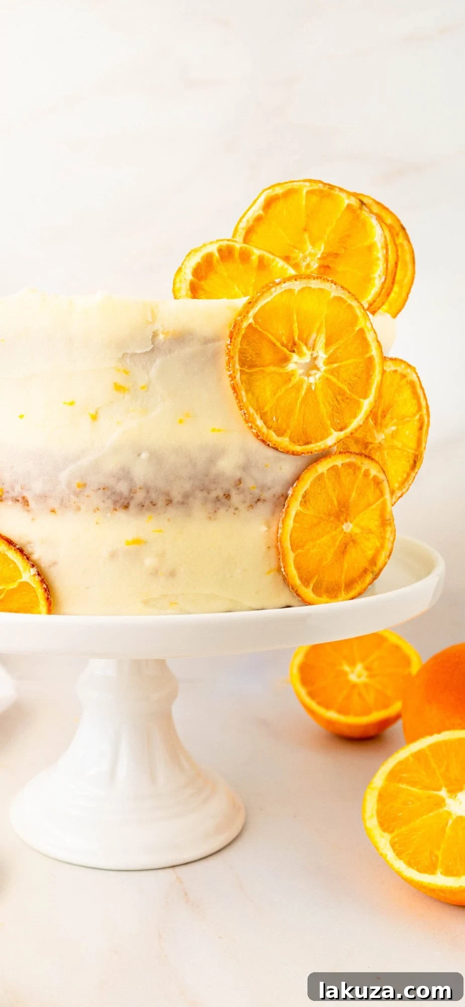 Zesty Orange Dream Cake 13 A vertical close-up of a beautifully decorated homemade orange cake with vibrant orange cream cheese frosting, garnished with dried orange slices. This moist and tender fresh orange cake delivers bright citrus flavor with fluffy layers, showcasing expert frosting and decoration. Ideal for both fully frosted and naked cake styles.