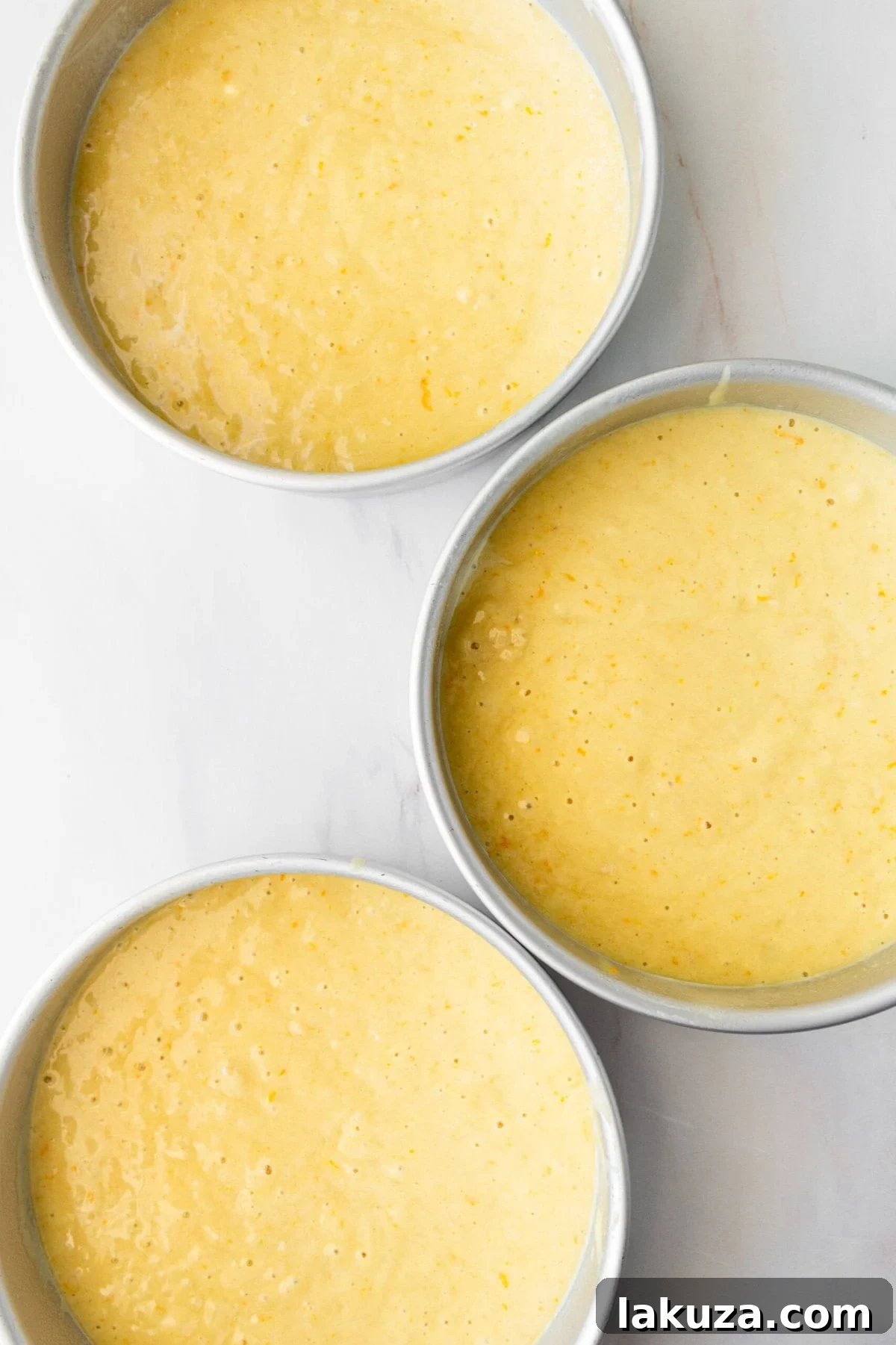 Zesty Orange Dream Cake 7 Three perfectly baked 8-inch orange cake layers stacked, showing their moist texture and vibrant color, ready for frosting.