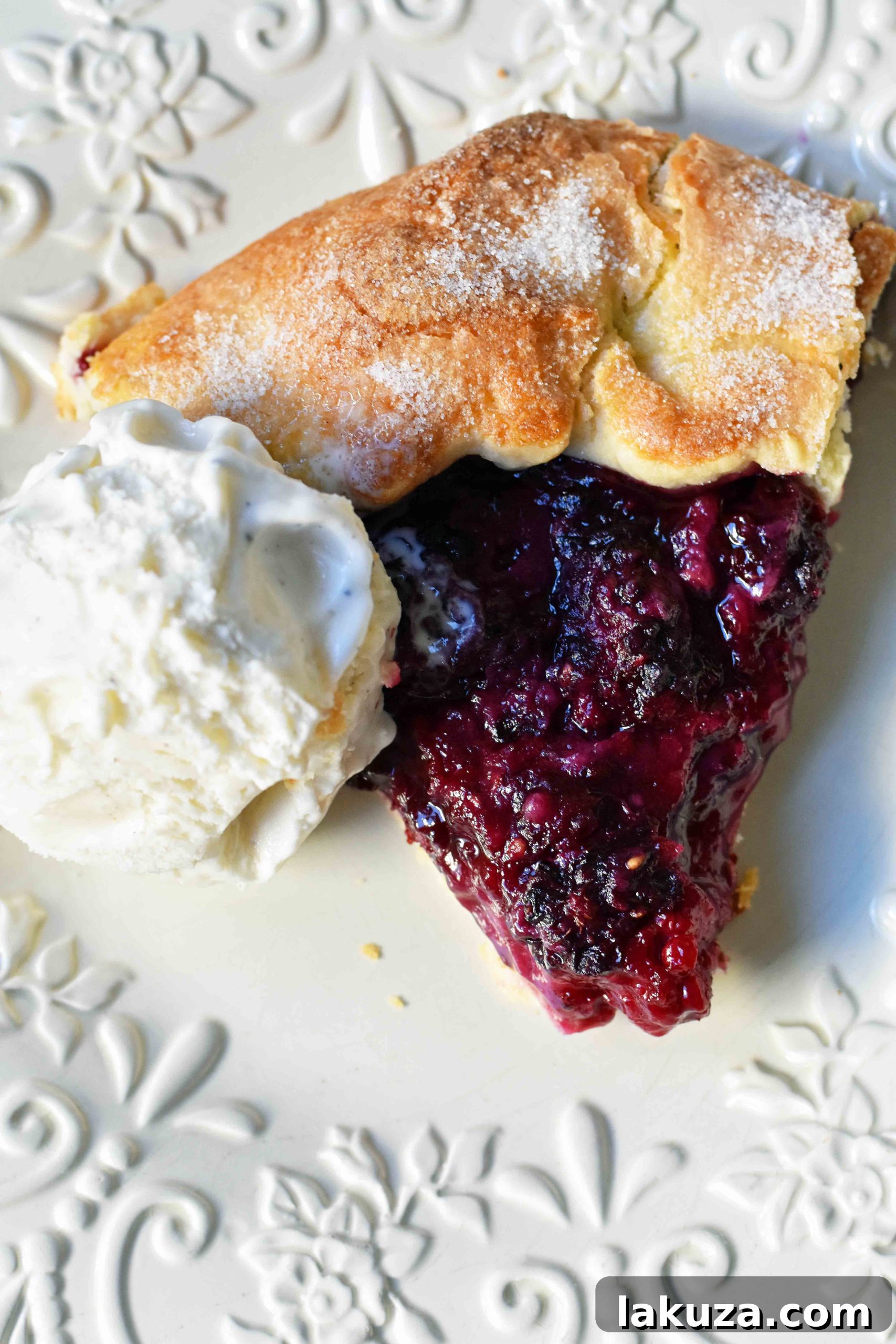 Rustic Blackberry Galette Crostata topped with a scoop of melting vanilla bean ice cream, ready to be served.