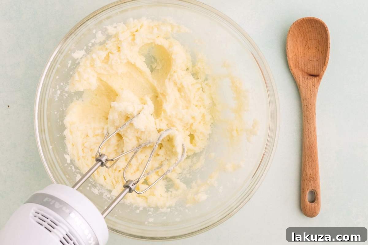 Overhead view of a hand mixer creaming butter and sugar in a bowl, creating a light and fluffy mixture.