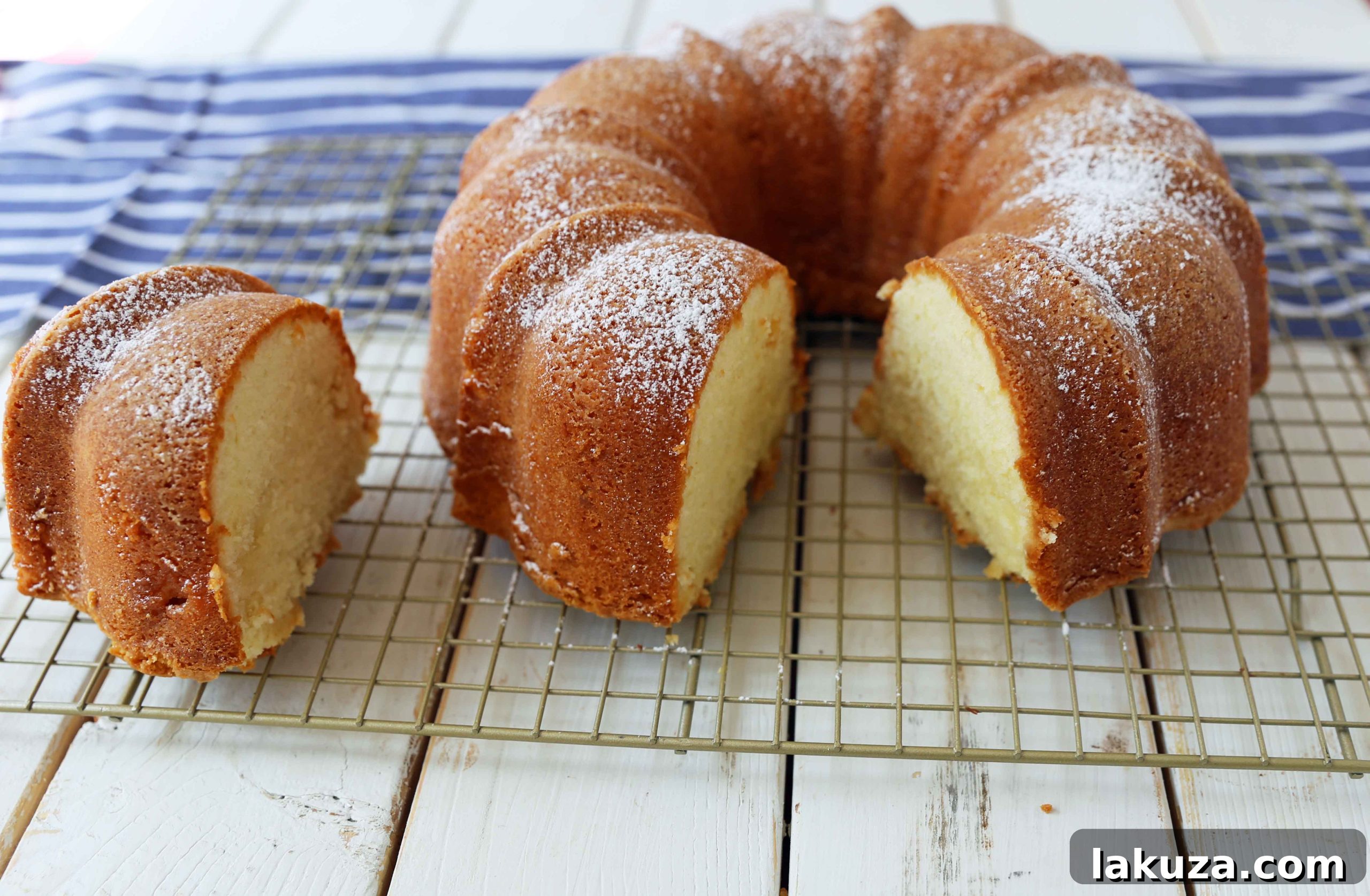A thick slice of cream cheese pound cake served on a white plate with fresh strawberries and homemade whipped cream.
