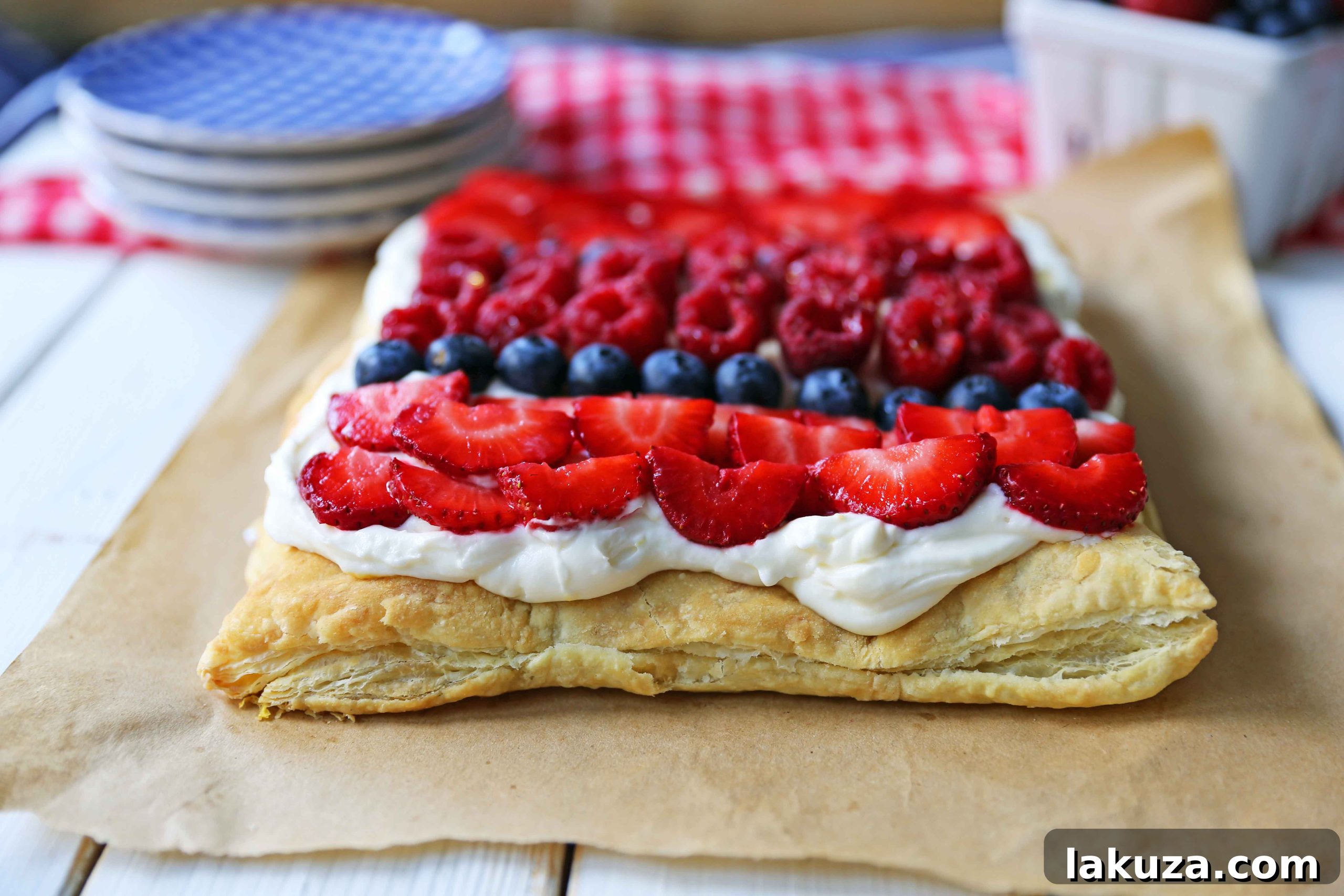A stunning Lemon Berry Cheesecake Puff Pastry tart displayed on a wooden board, garnished with a generous assortment of fresh, colorful berries ready to be served.