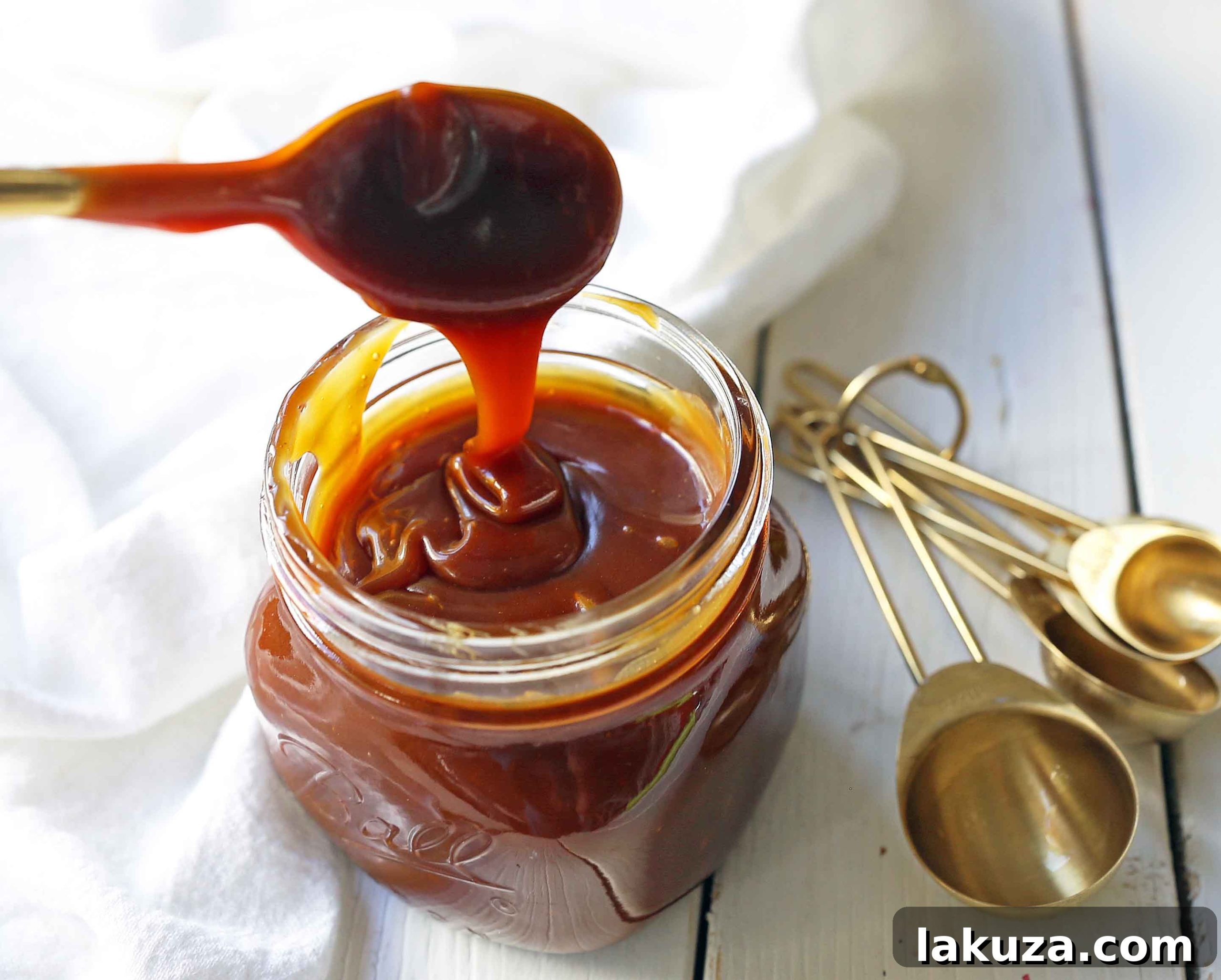 Ladle pouring thick, golden homemade salted caramel sauce into a serving bowl, highlighting its rich texture.