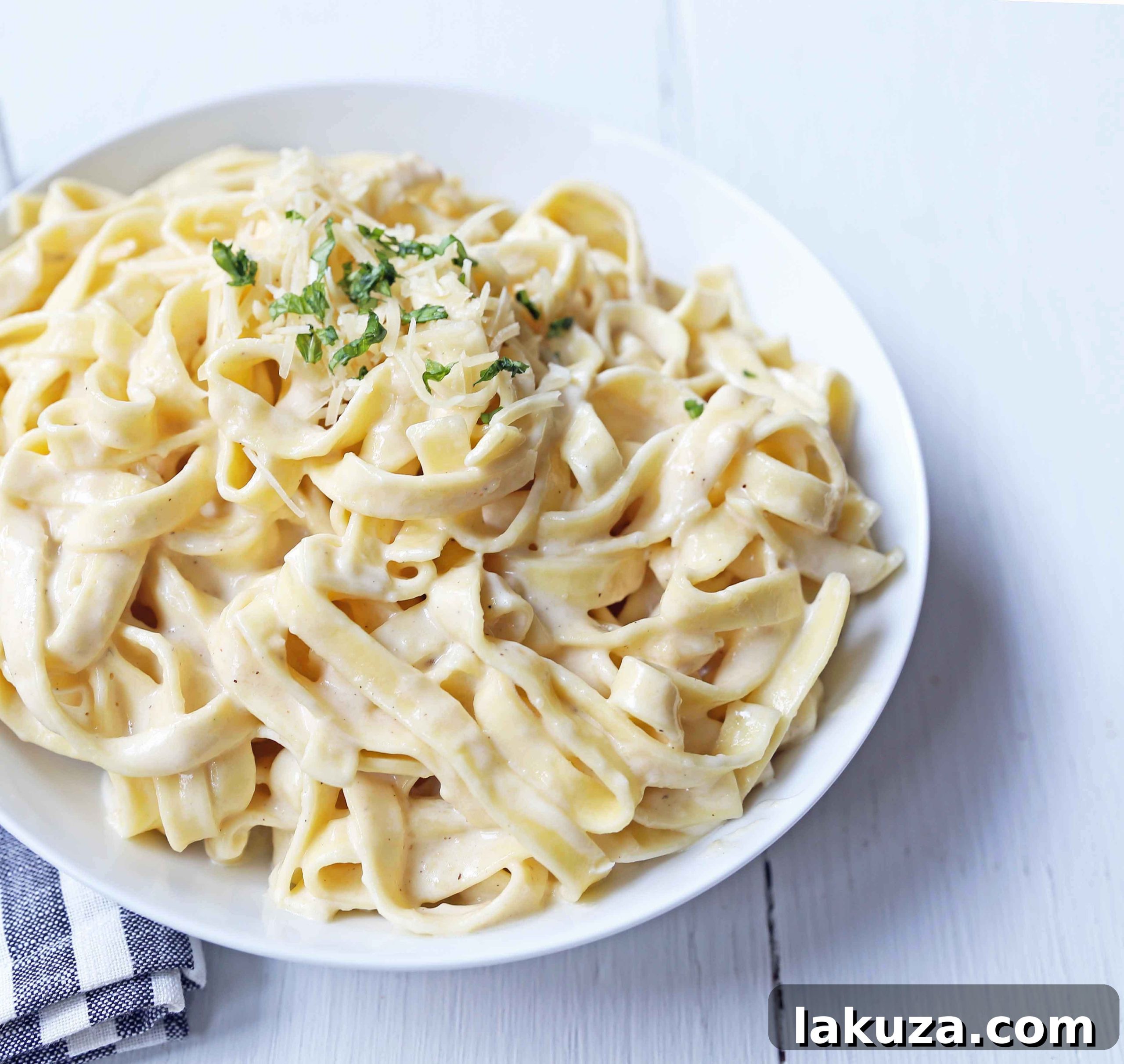 Fettuccine Alfredo preparation: Freshly grated Parmesan cheese and simmering heavy cream combine to form a smooth, garlic-infused homemade Alfredo sauce, ready to be tossed with al dente fettuccine.