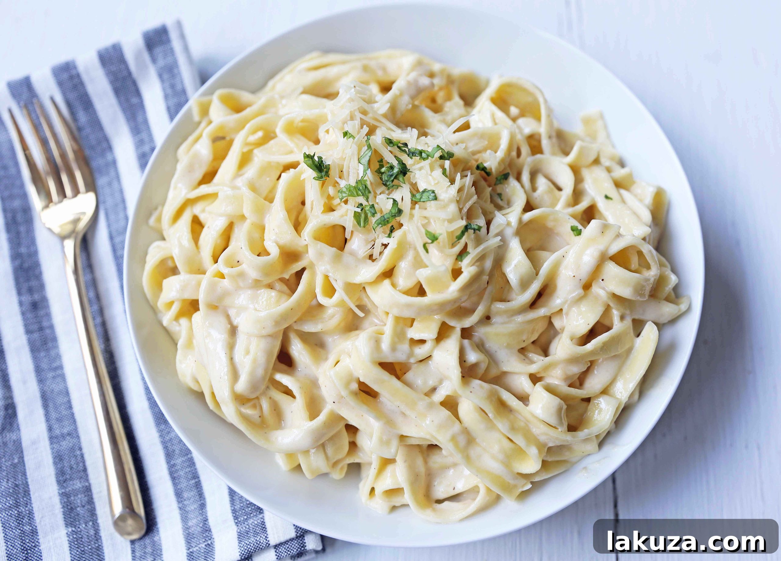 Fettuccine Alfredo served in a bowl, garnished with fresh Italian parsley and extra grated Parmesan. The best homemade pasta dish for family dinners or special occasions.
