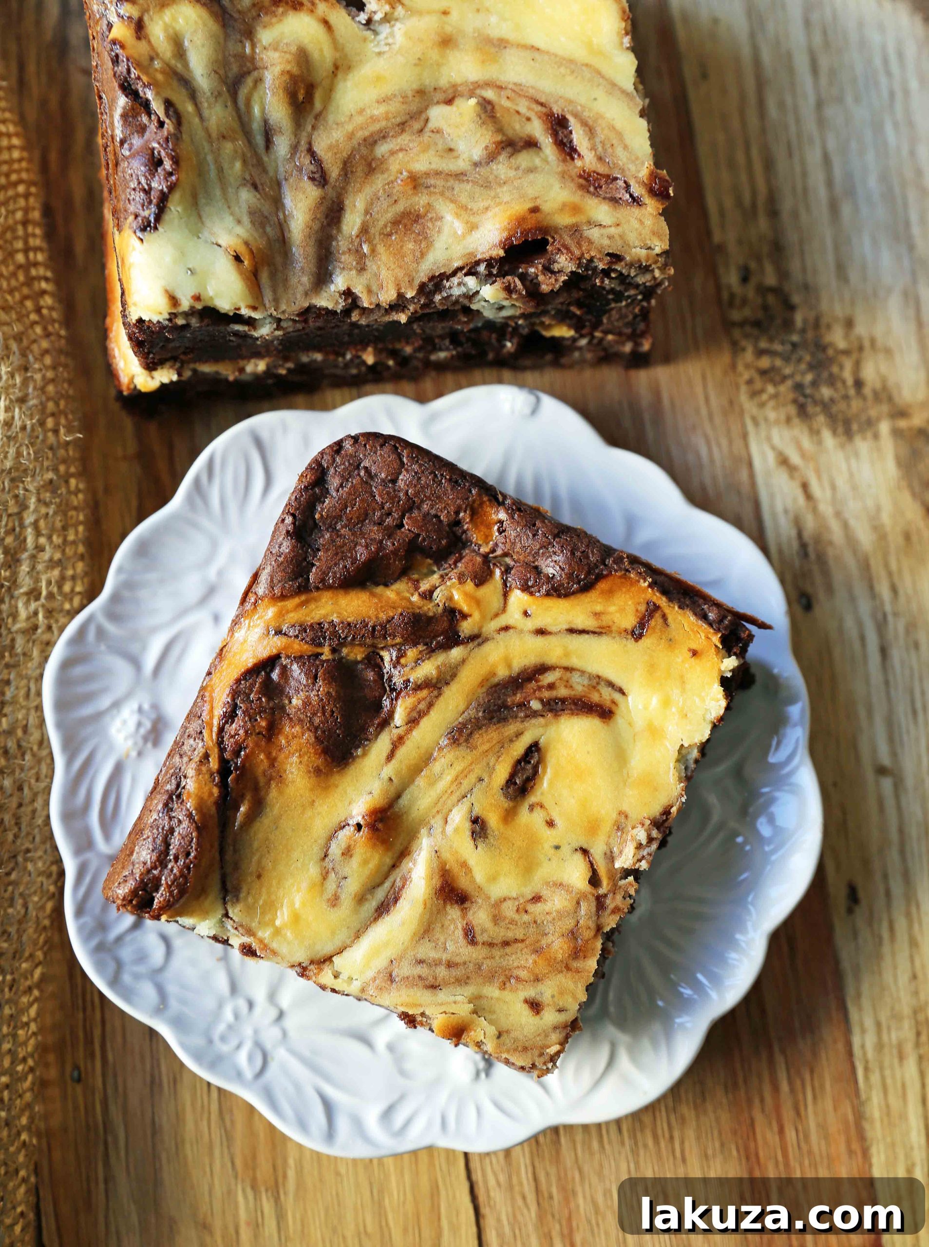 Decadent Cheesecake Brownies 5 Hand holding a spatula to lift a perfectly cut cheesecake brownie square from the pan, ready to be enjoyed.