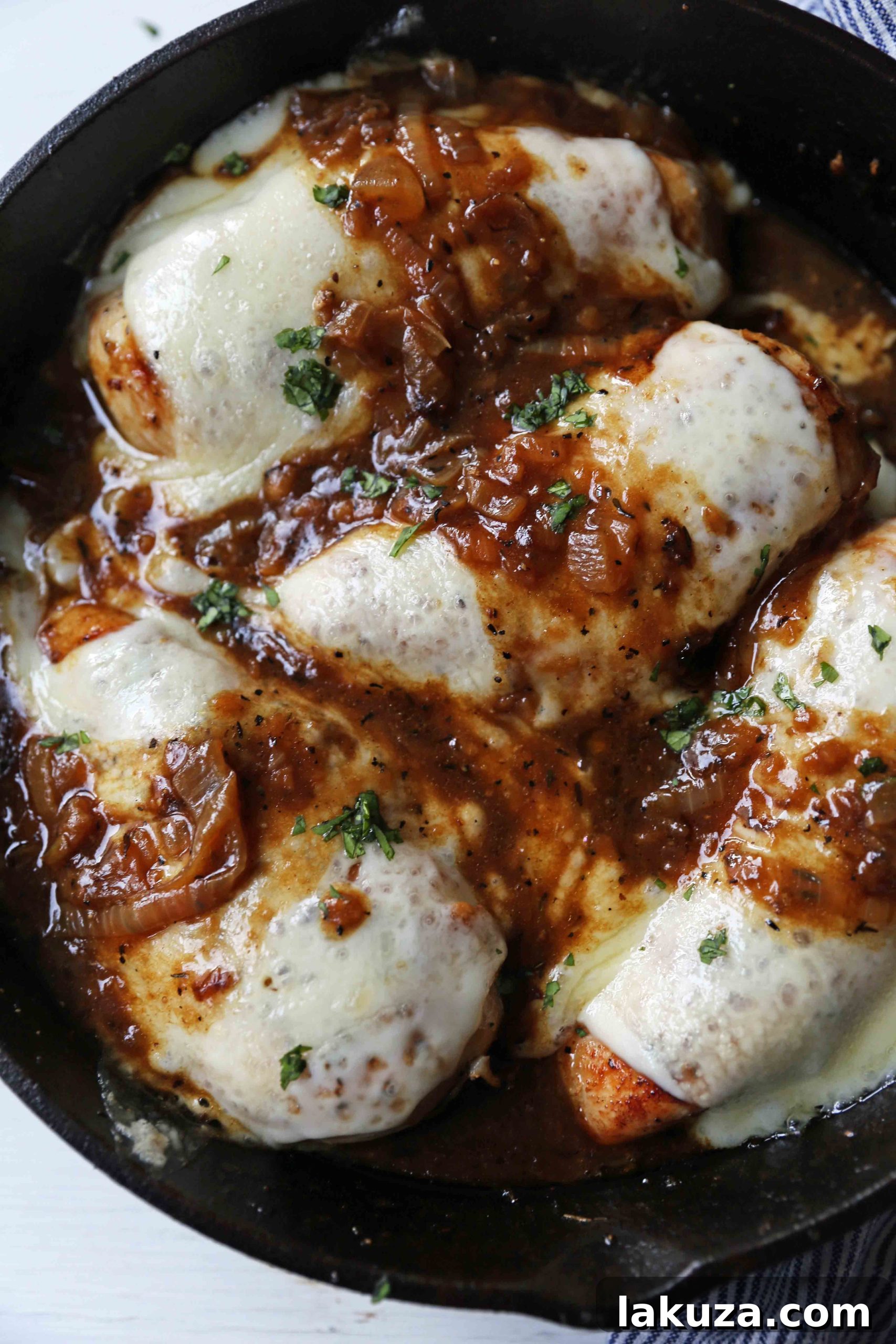 Golden French Onion Chicken 6 An overhead shot of French Onion Chicken in a skillet, showcasing the golden-brown crust of the chicken, the glistening caramelized onions, and the perfectly melted cheese on top. #ComfortFoodRecipes #WeeknightDinner