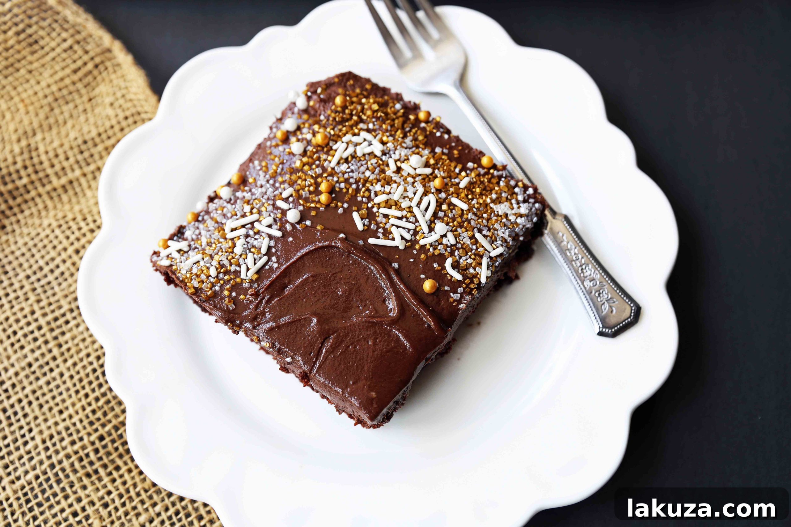 Close-up of a slice of moist chocolate sheet cake, revealing its tender crumb and generous, creamy milk chocolate frosting.