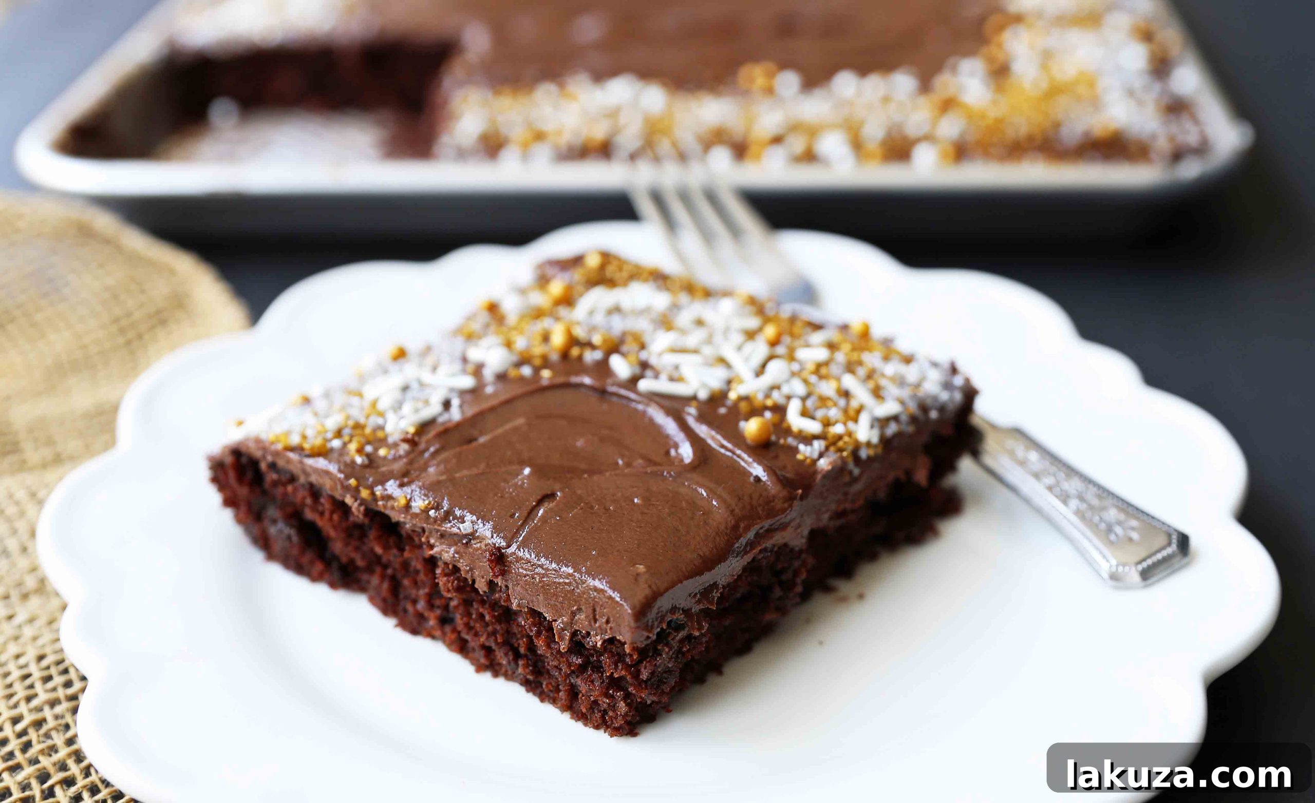 A beautifully frosted chocolate sheet cake, generously covered with smooth milk chocolate frosting and ready to be sliced, garnished with chocolate shavings.