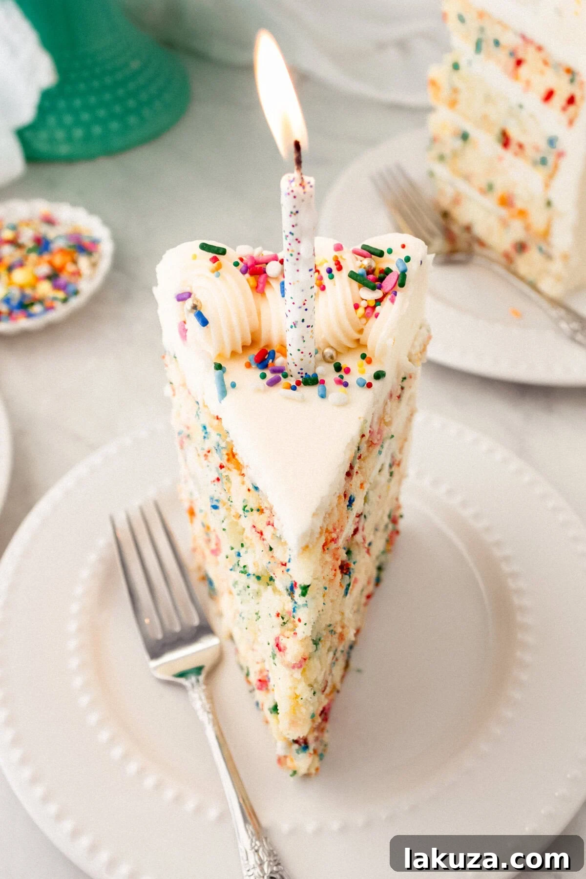 Joyful Sprinkle Celebration 2 A beautifully decorated slice of homemade Funfetti cake with rainbow sprinkles, topped with cream cheese frosting and a birthday candle, ready for celebration.