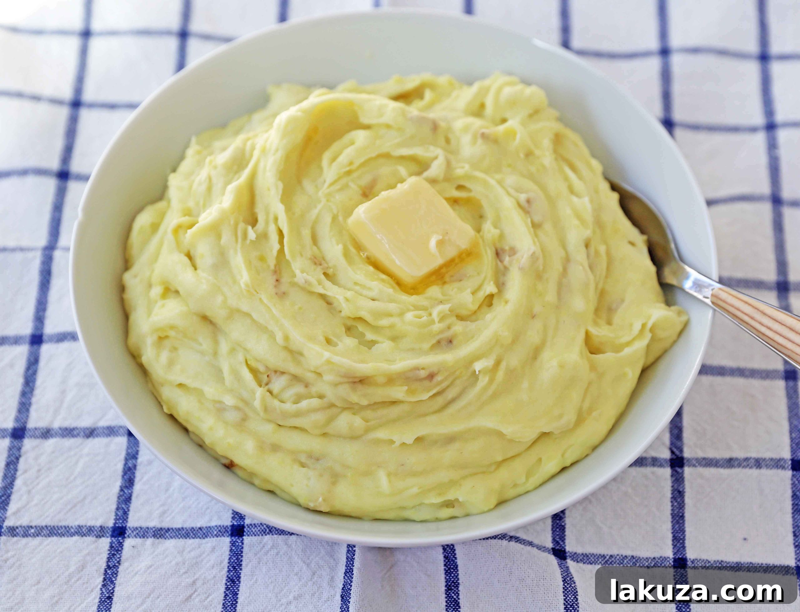 Velvety Smooth Mashed Potatoes 4 A close-up of beautifully plated creamy mashed potatoes, garnished with a sprig of fresh herbs, highlighting their smooth texture and appetizing appeal.