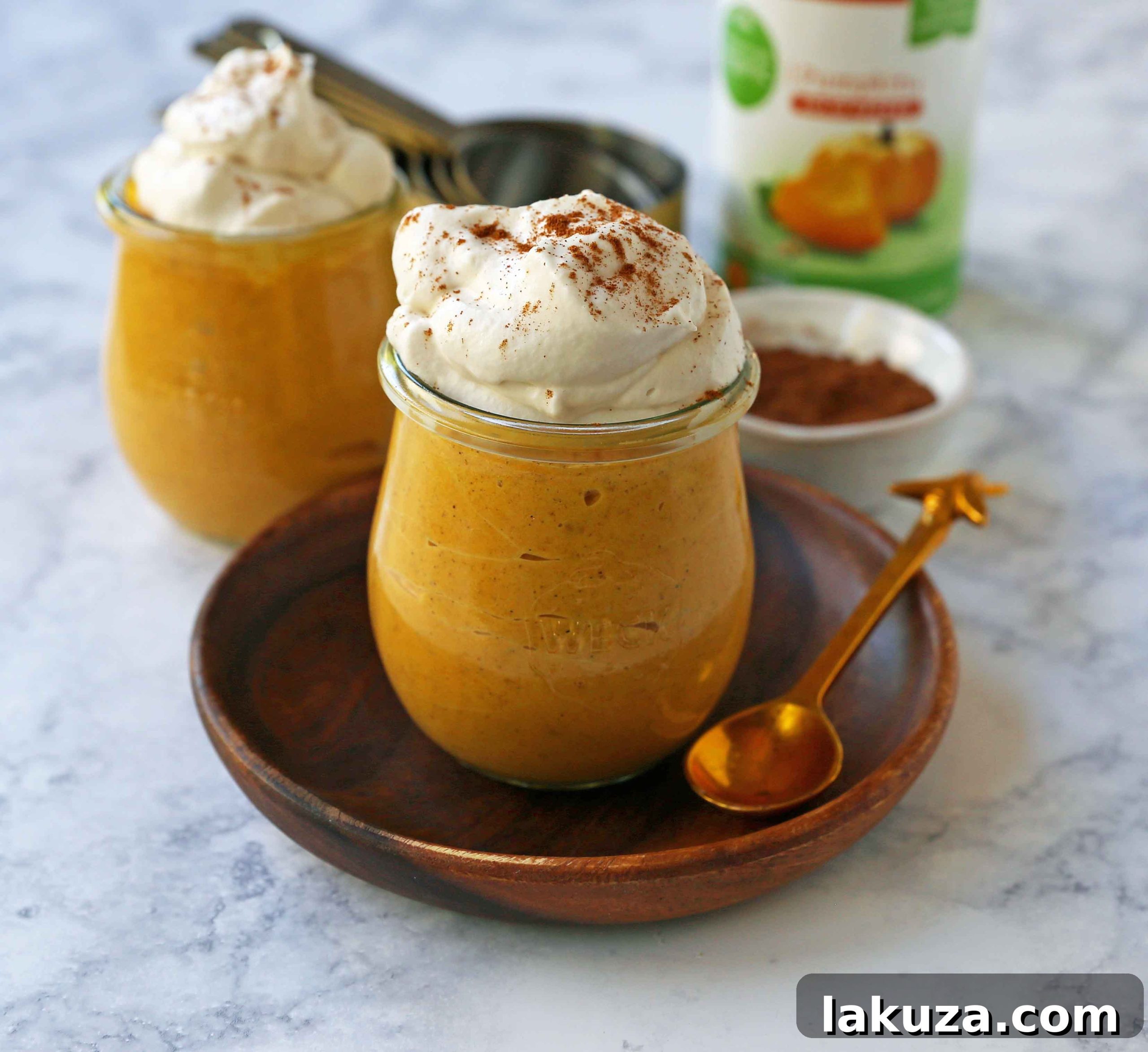 Ingredients for sugar-free pumpkin cheesecake mousse laid out: pumpkin puree can, cream cheese block, maple syrup, heavy cream, pumpkin pie spice, and vanilla extract.