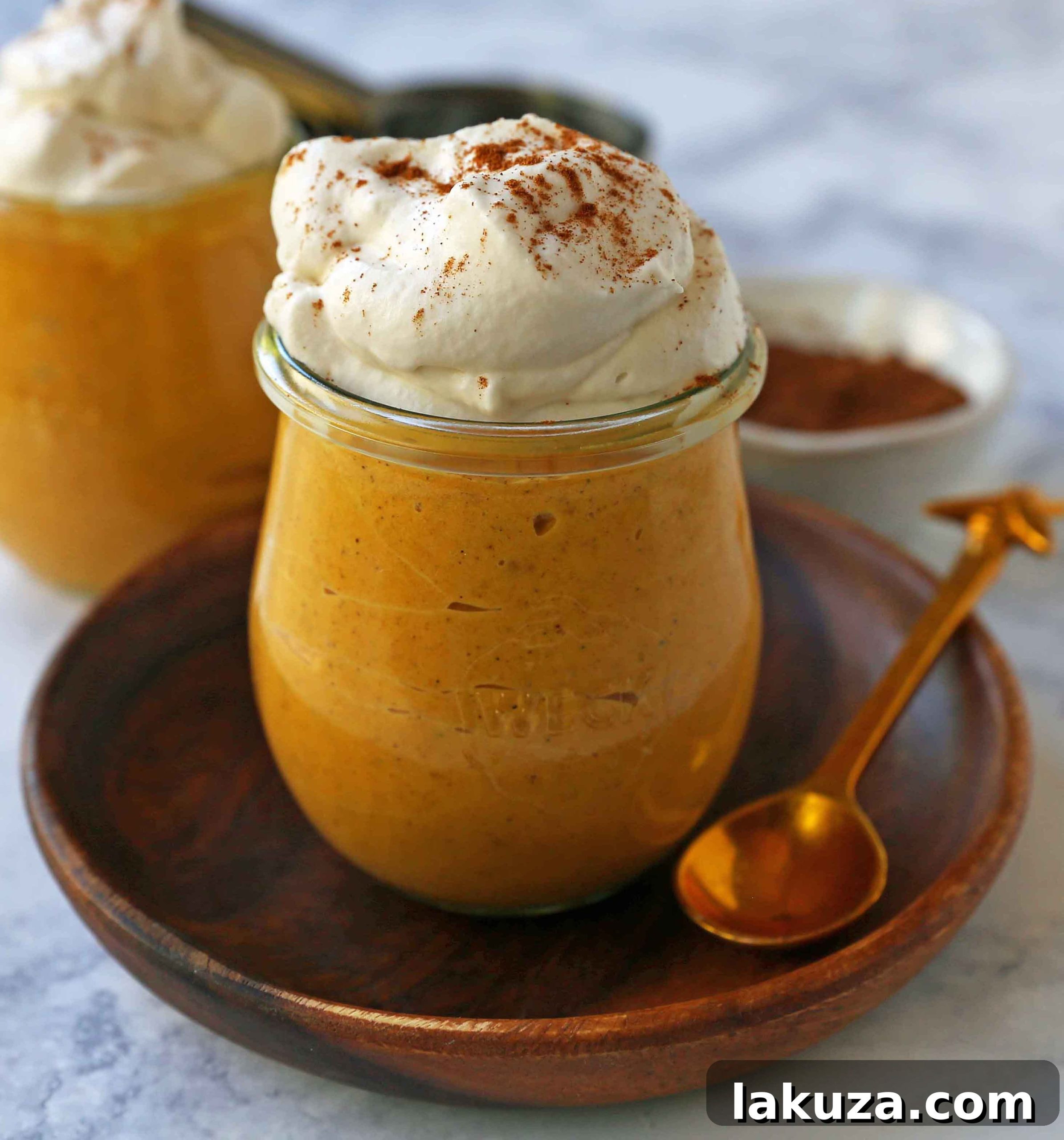 Individual serving of sugar-free pumpkin cheesecake mousse topped with fresh whipped cream and a light dusting of cinnamon, ready to be enjoyed.