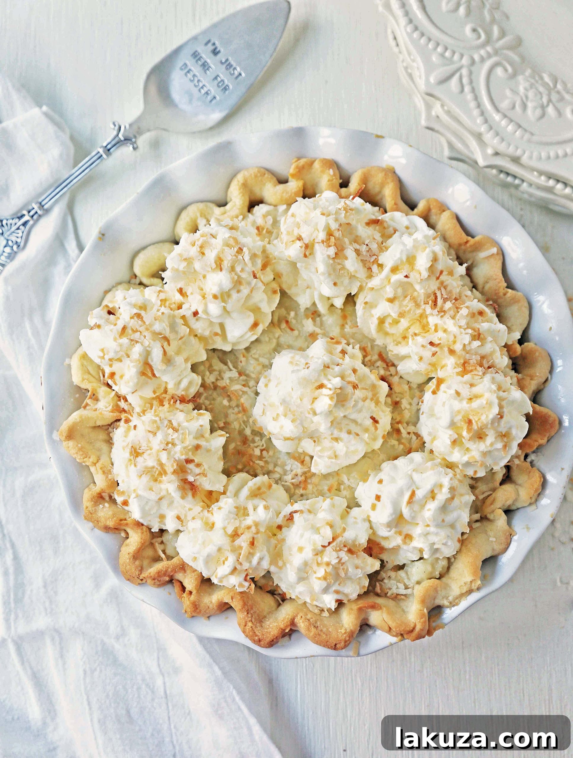 Several slices of Coconut Cream Pie artfully arranged on a white serving platter, garnished with toasted coconut.