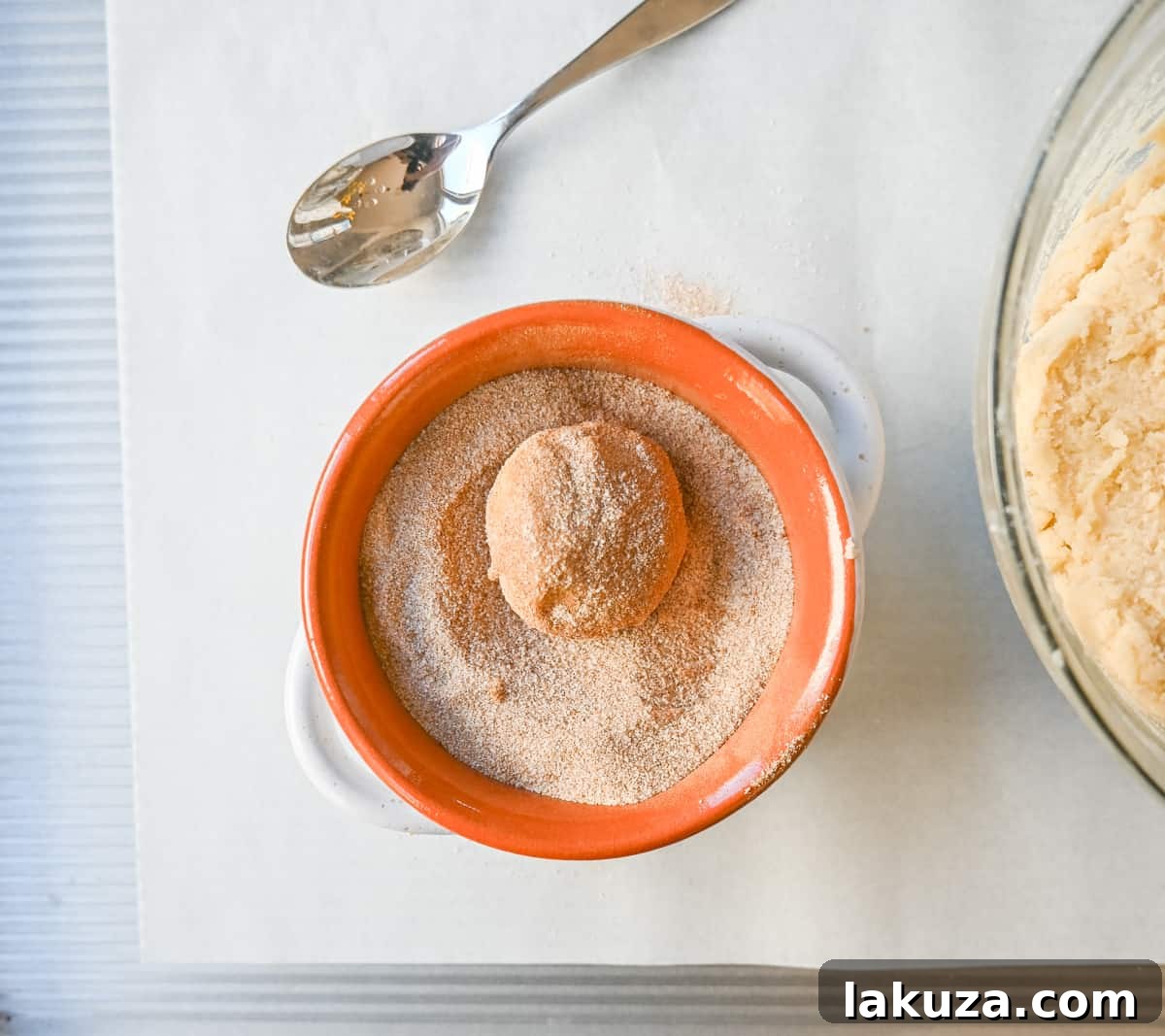 Snickerdoodle cookie dough rolling into cinnamon sugar mixture