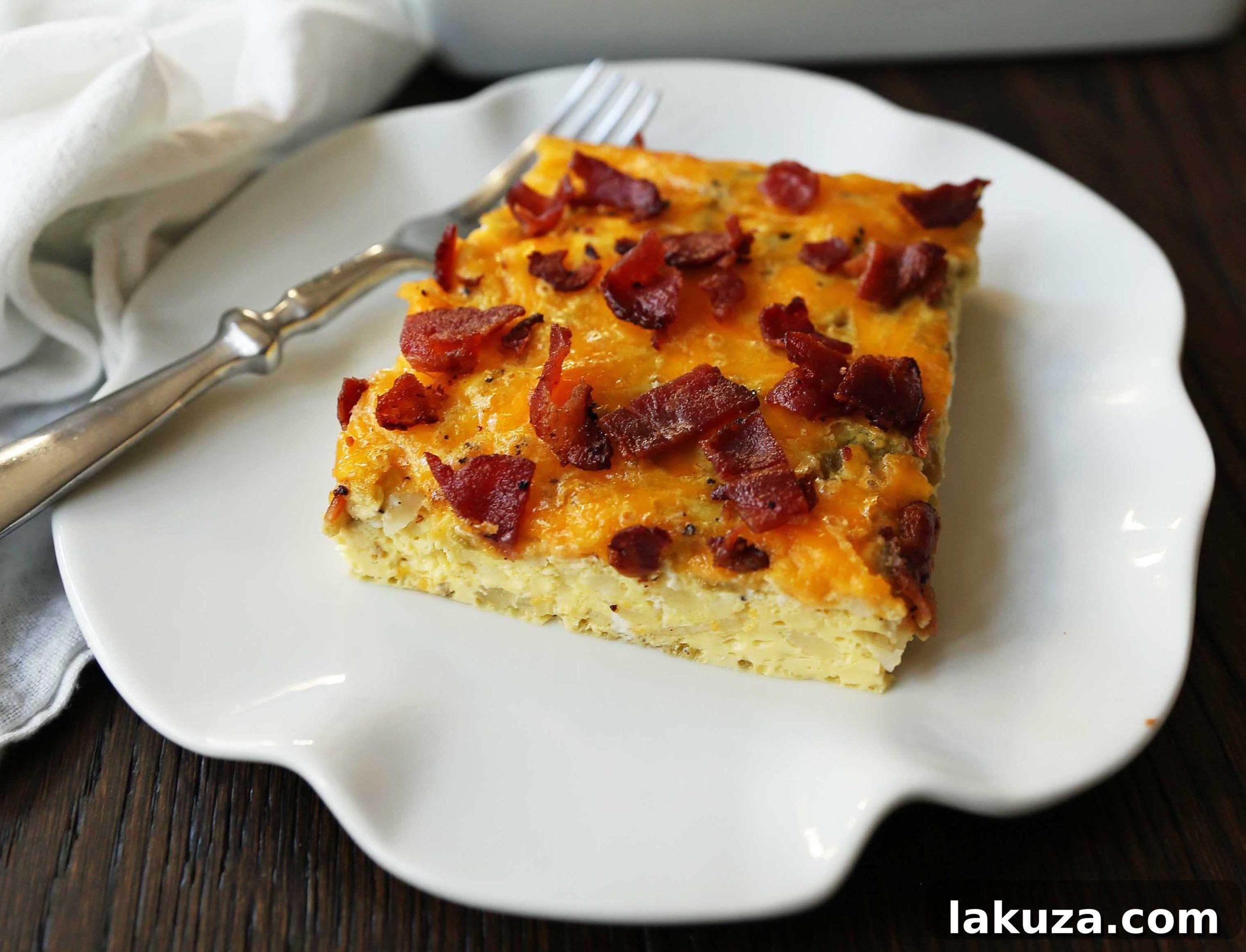 Savory Breakfast Bake 6 Close-up of a slice of Bacon Egg and Cheese Casserole, showing the layers of eggs, cheese, potatoes, and bacon. Ready for a delicious breakfast.