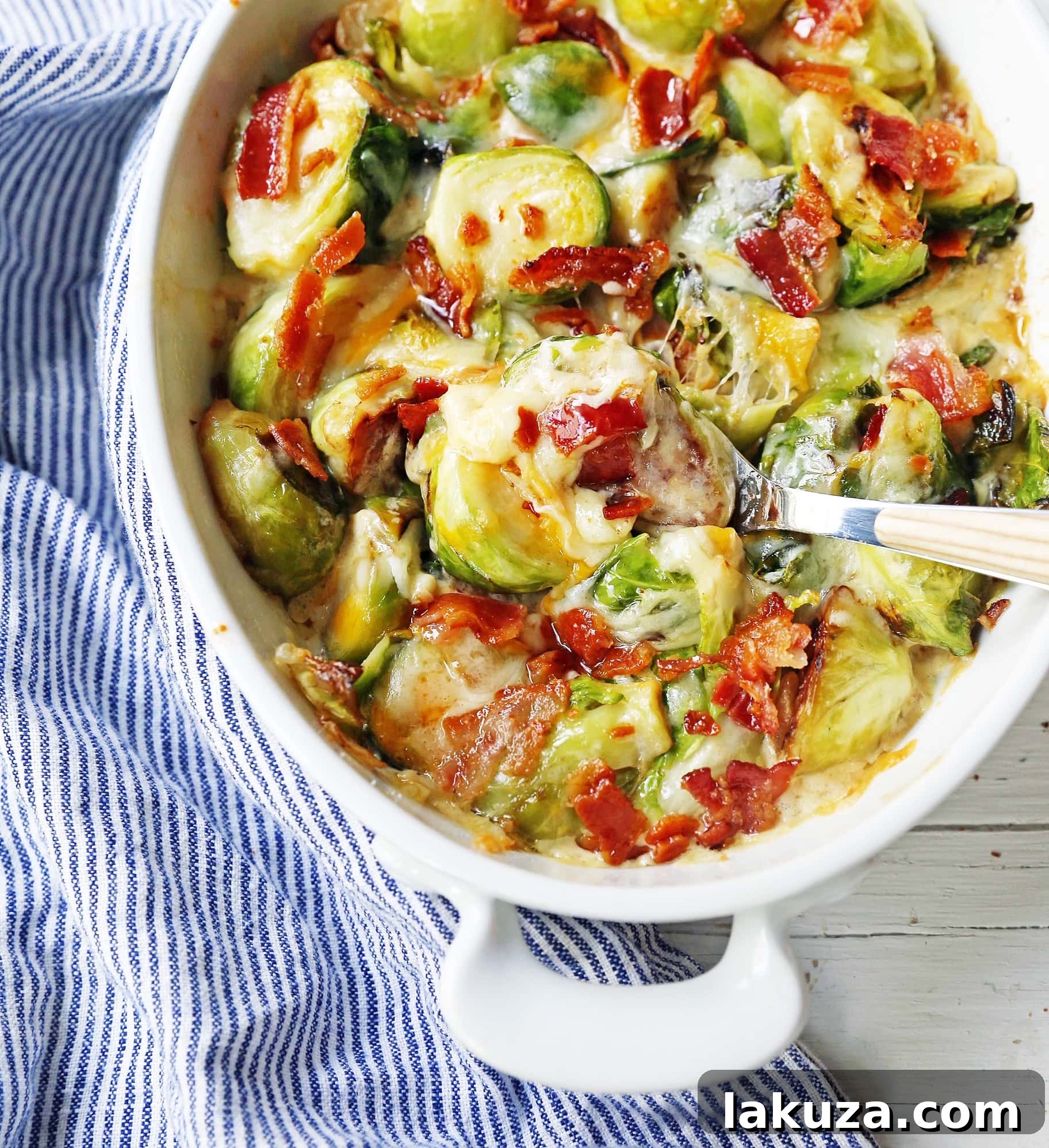 A serving of creamy cheesy brussels sprouts with bacon in a white bowl.