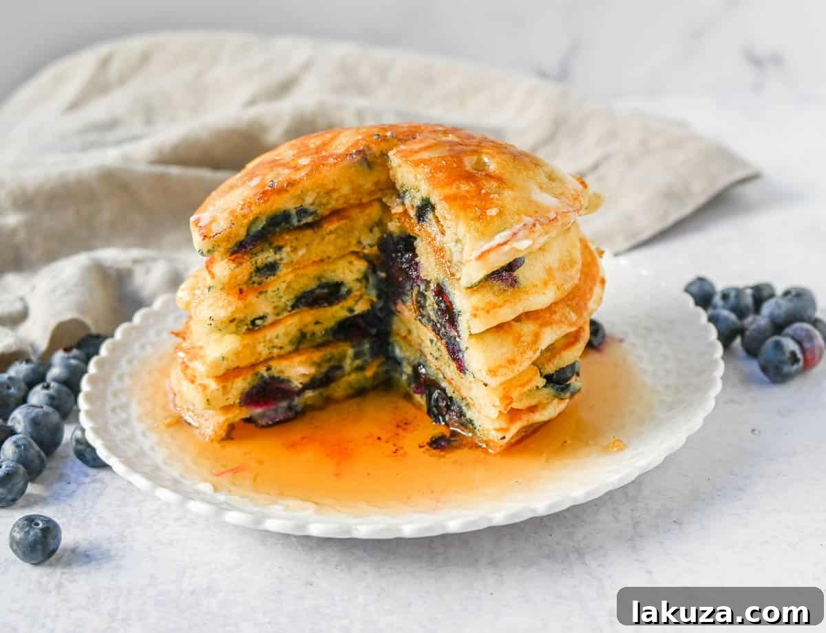 Bursting Blueberry Pancakes 3 Close-up of fluffy buttermilk blueberry pancakes cooking on a griddle, showing golden edges and popping blueberries.