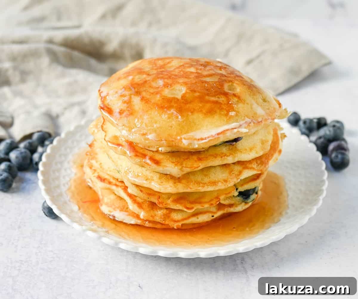 Bursting Blueberry Pancakes 4 Hand sprinkling fresh blueberries onto pancake batter cooking on a hot griddle for even distribution.