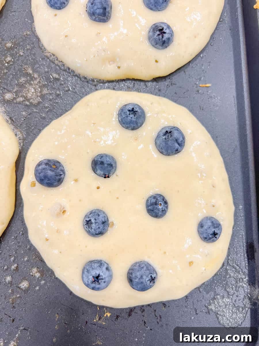 Bursting Blueberry Pancakes 8 Pancake batter being poured onto a buttered griddle, ready for blueberries.