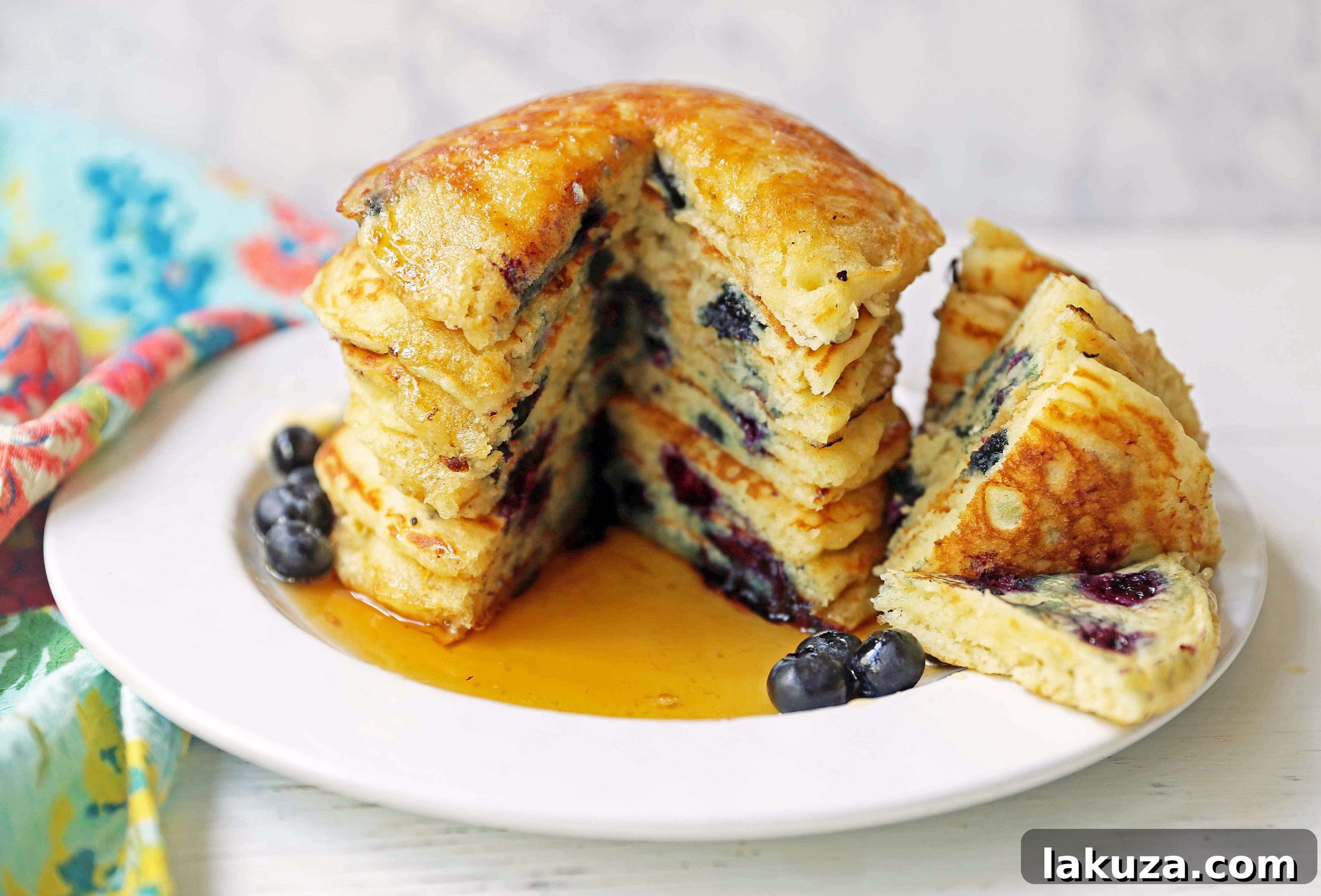 Bursting Blueberry Pancakes 10 A large platter piled high with freshly made fluffy buttermilk blueberry pancakes, garnished with fresh blueberries.