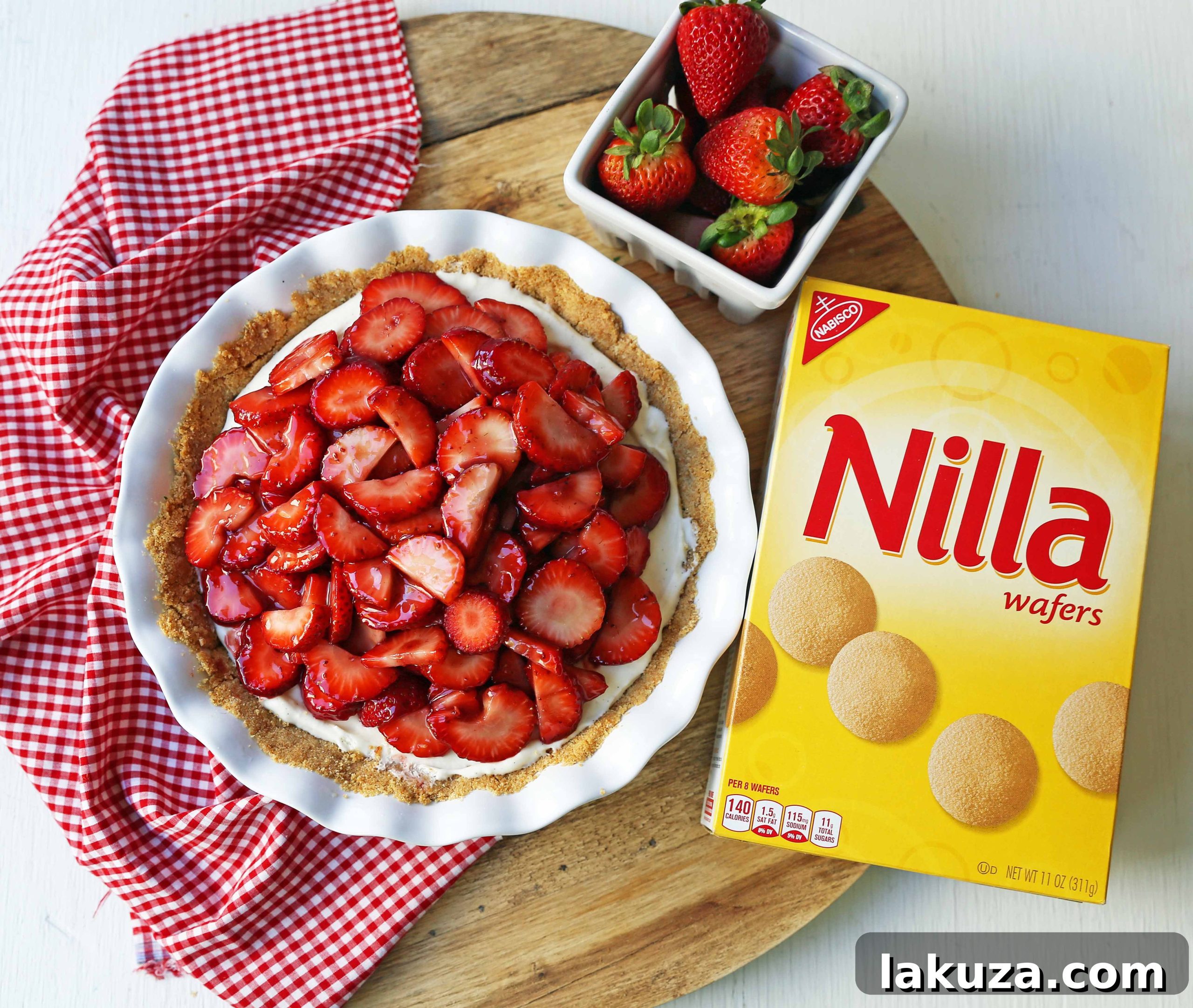 A slice of Strawberry Cream Cheese Pie on a white plate, showcasing the creamy filling, glazed strawberries, and golden cookie crust.