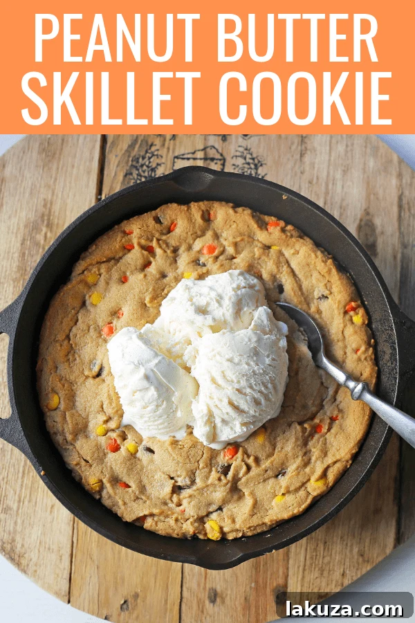 Large Peanut Butter Skillet Cookie, sliced into wedges, topped with melting vanilla ice cream and hot fudge, ready to be served.
