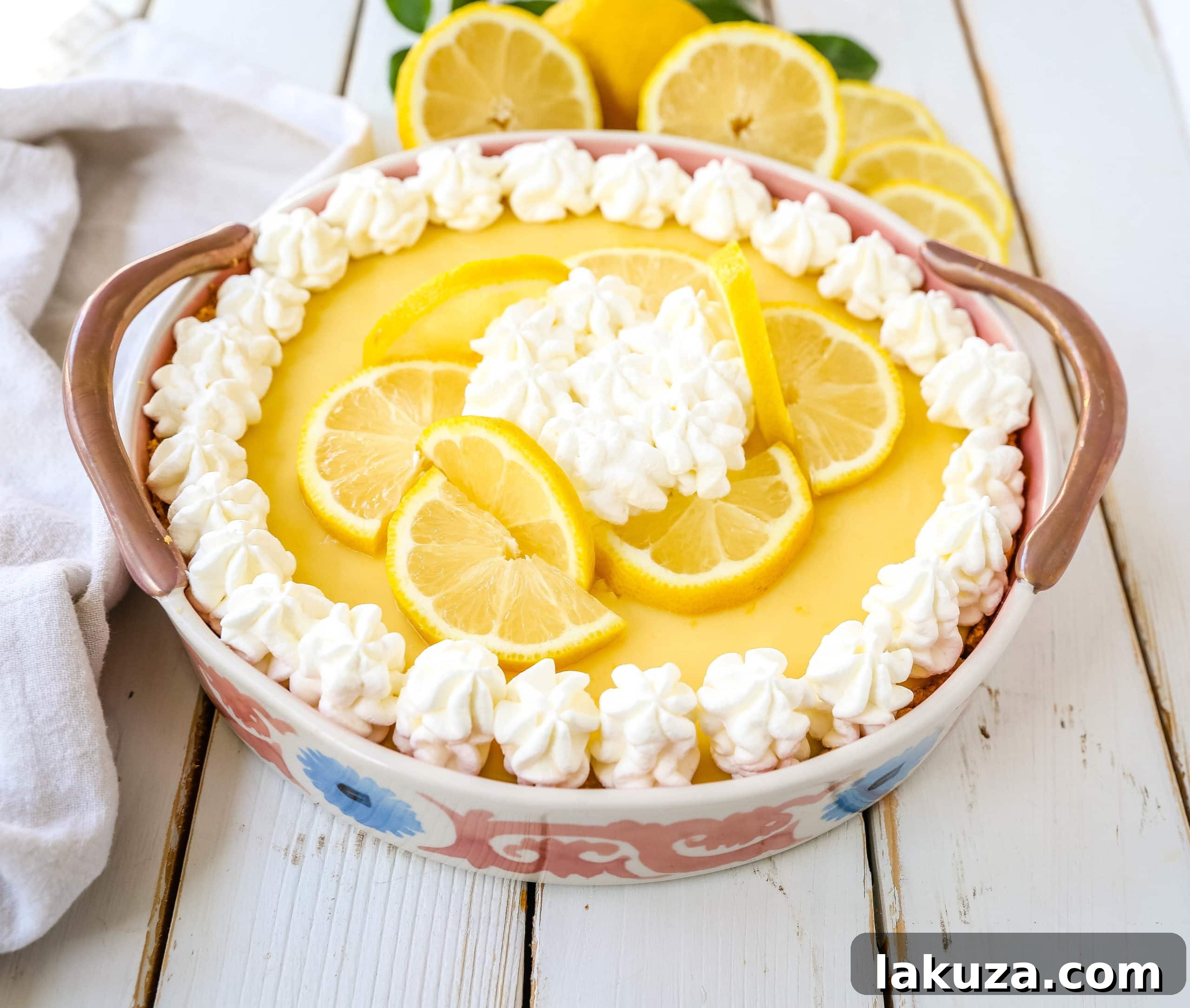 A close-up of a slice of Lemon Cream Pie, showcasing its smooth, creamy filling and golden graham cracker crust, garnished with fresh lemon zest and whipped cream.