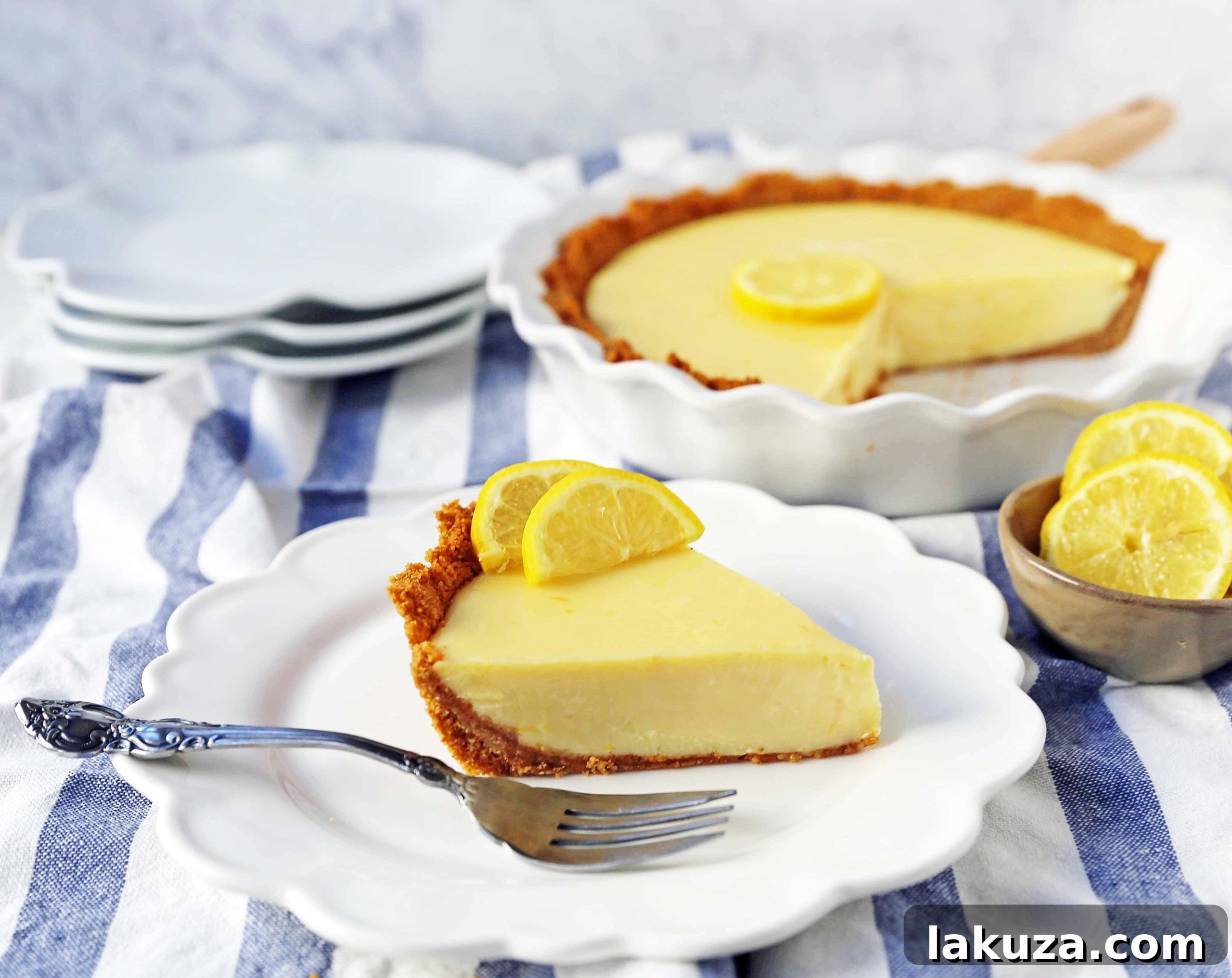 A slice of Lemon Cream Pie, generously topped with homemade whipped cream and a sprinkle of fresh lemon zest, ready to be served.