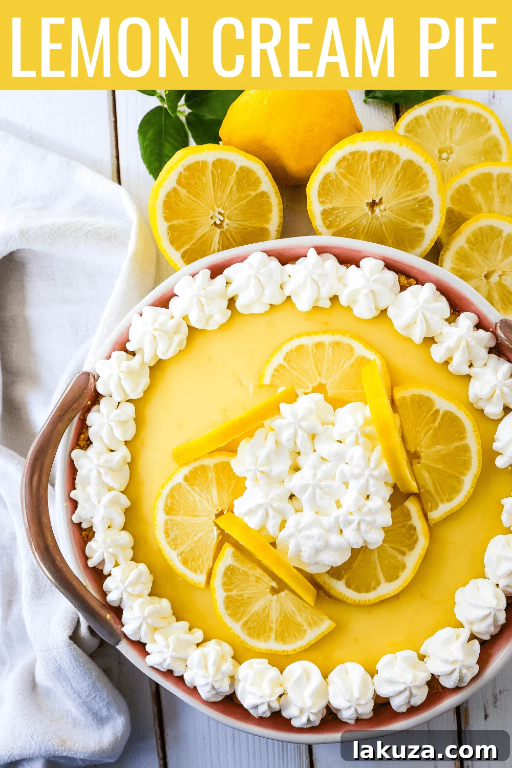 A close-up of a single slice of Lemon Cream Pie, garnished with a dollop of whipped cream and a twist of lemon peel, presented on a white plate.