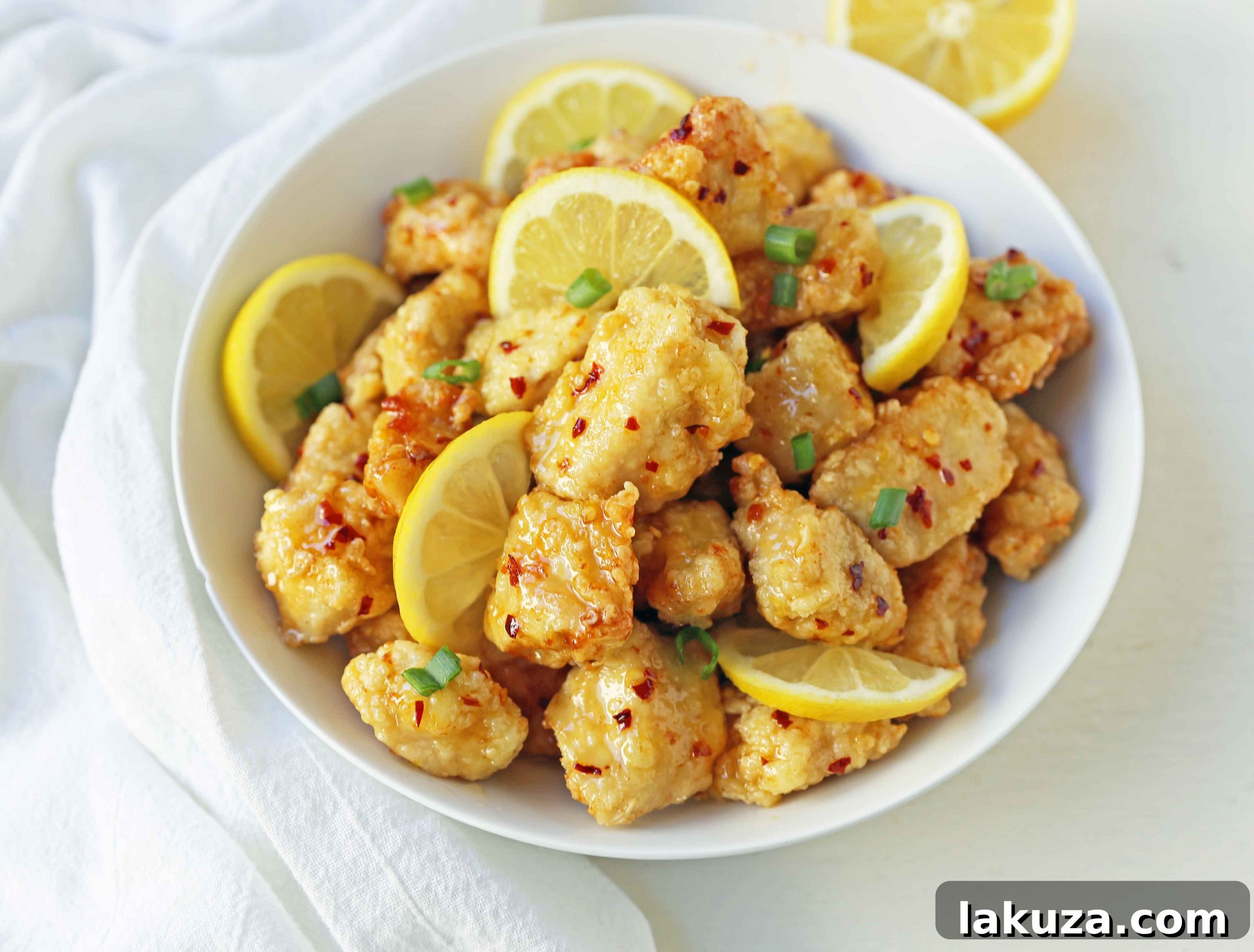 Golden Crispy Lemon Chicken 4 Platter of homemade Chinese Lemon Chicken, featuring tender, crispy chicken pieces generously coated in a sweet and sour lemon sauce, ready to be served.