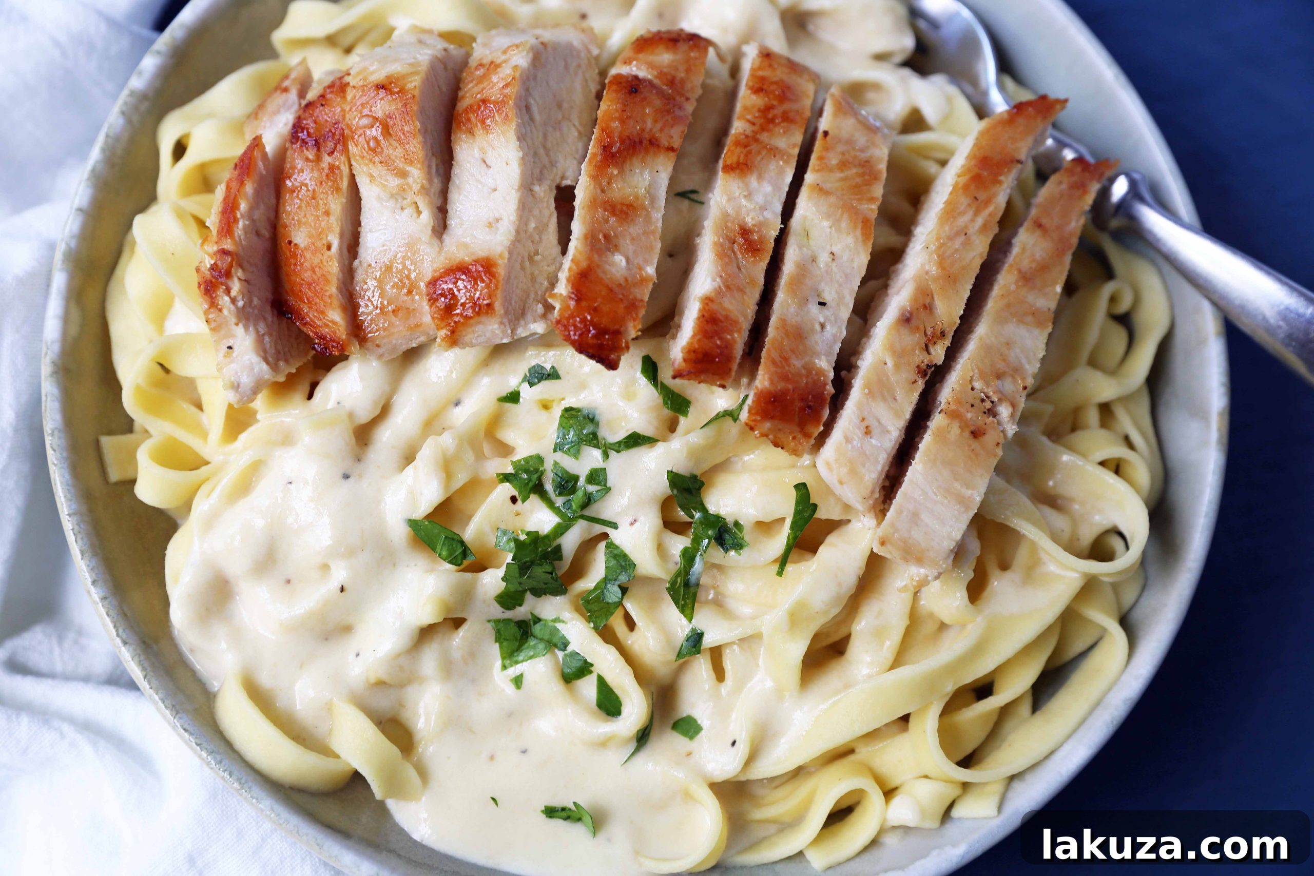 Creamy Chicken Fettuccine Delight 4 A bowl of Chicken Fettuccine Alfredo, featuring creamy sauce, delicate pasta, and sliced chicken breast, ready to be enjoyed.