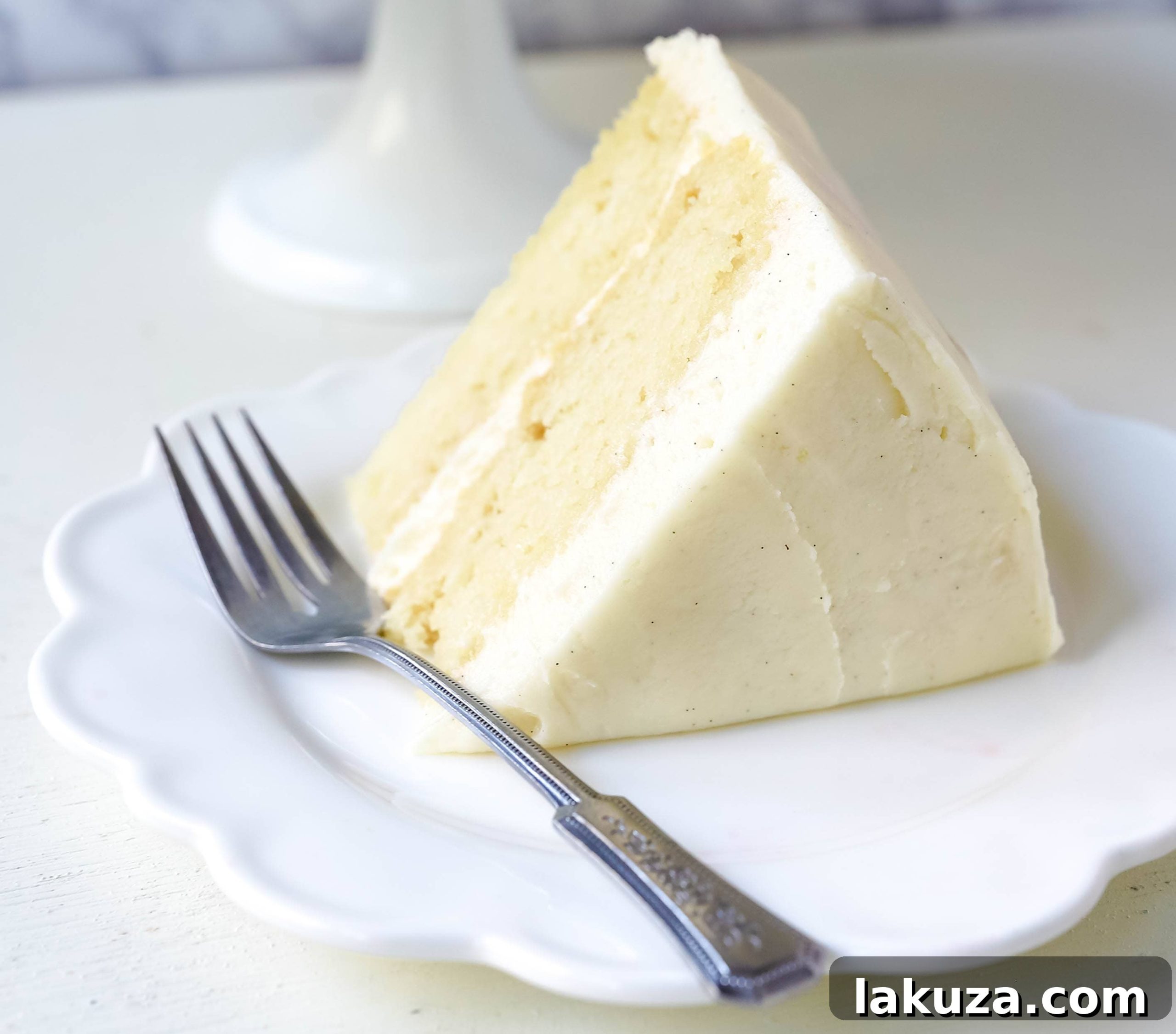 Close-up of a vanilla cake with rich vanilla bean frosting, ready to be sliced.