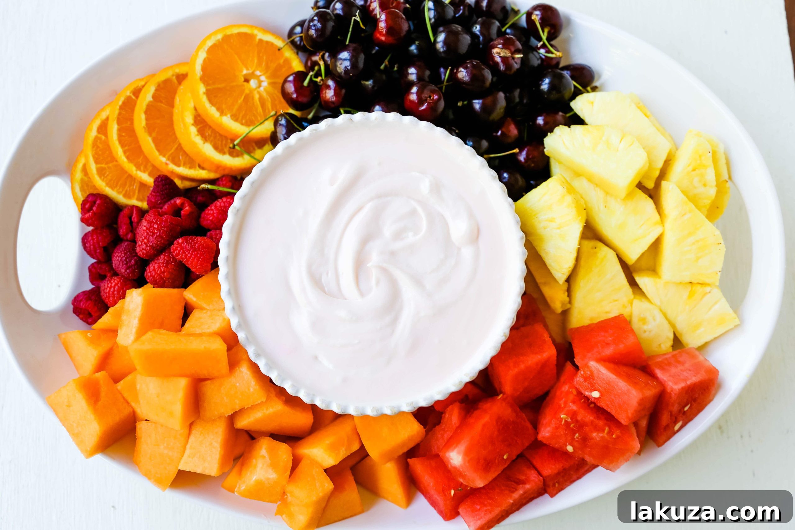Creamy Fruit Delight 4 Fluffy fruit dip in a bowl, showcasing its smooth, light texture, with fresh berries and pineapple in the background.