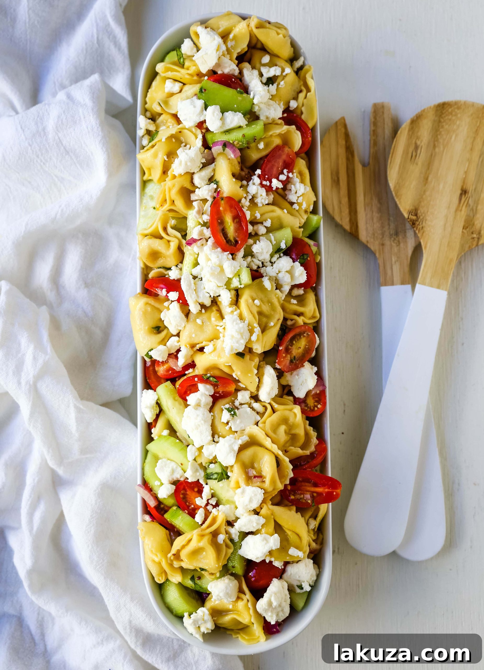 Fresh ingredients for Greek Tortellini Pasta Salad: halved cherry tomatoes, diced cucumbers, and thinly sliced red onions, ready to be mixed.