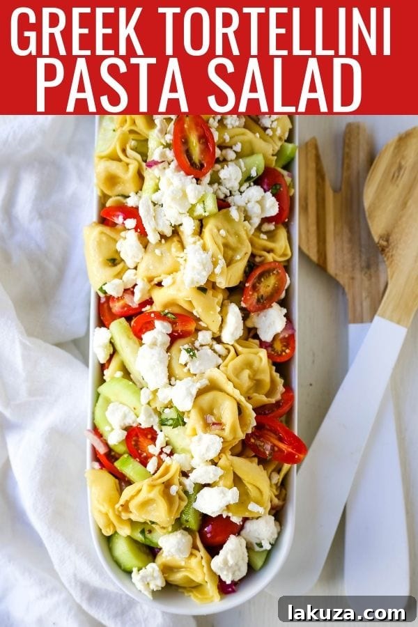 A close-up shot of Greek Tortellini Pasta Salad in a serving bowl, ready to be enjoyed. Highlighted are the fresh ingredients and the rich texture of the tortellini.