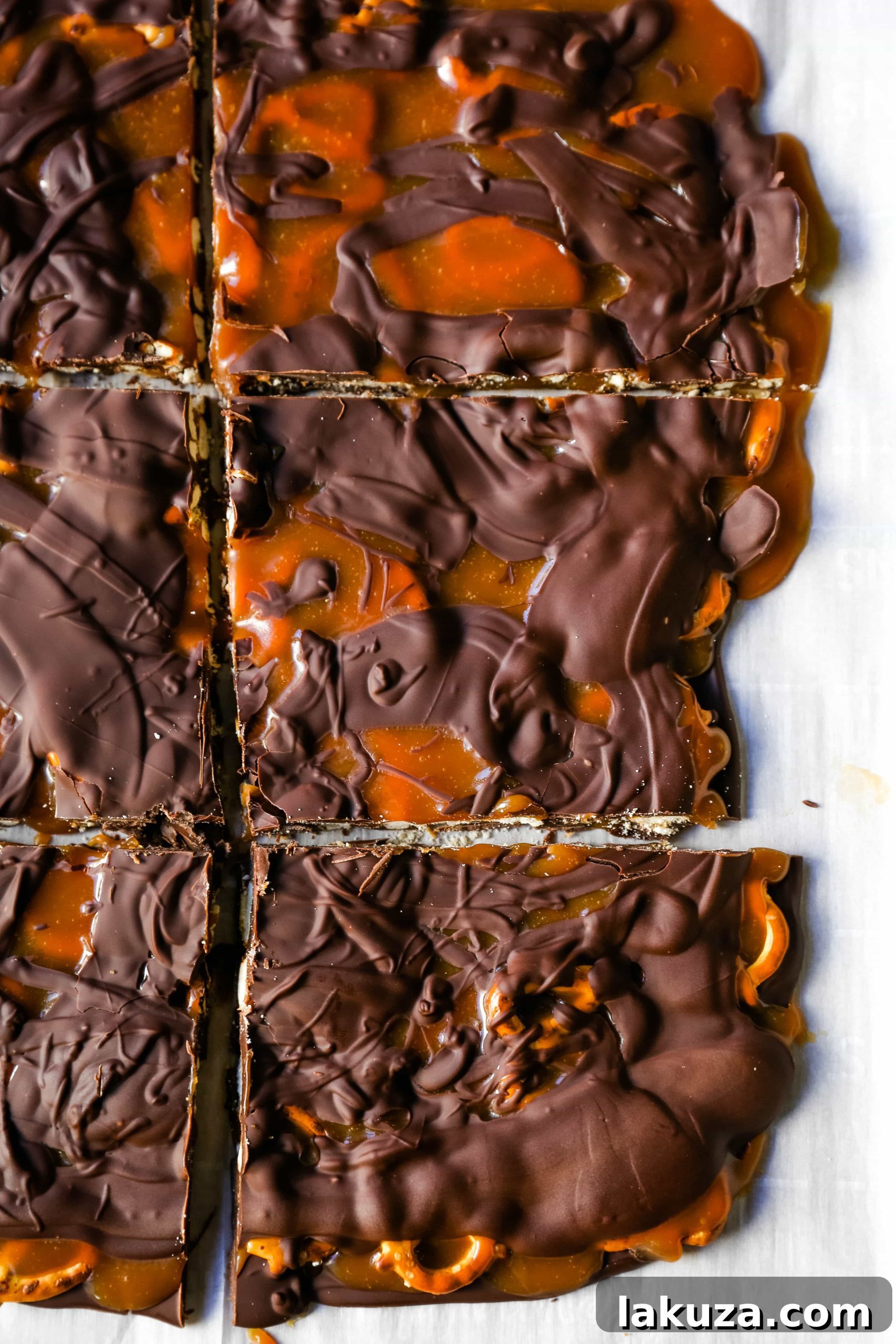 Salty-Sweet Chocolate Caramel Pretzel Crunch 5 A baking sheet filled with a base layer of melted semi-sweet chocolate, topped with crunchy mini pretzels, ready for the caramel and milk chocolate layers of the bark.